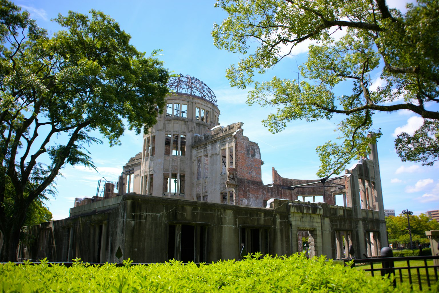 Hiroshima Peace Memorial with surrounding trees and blue sky