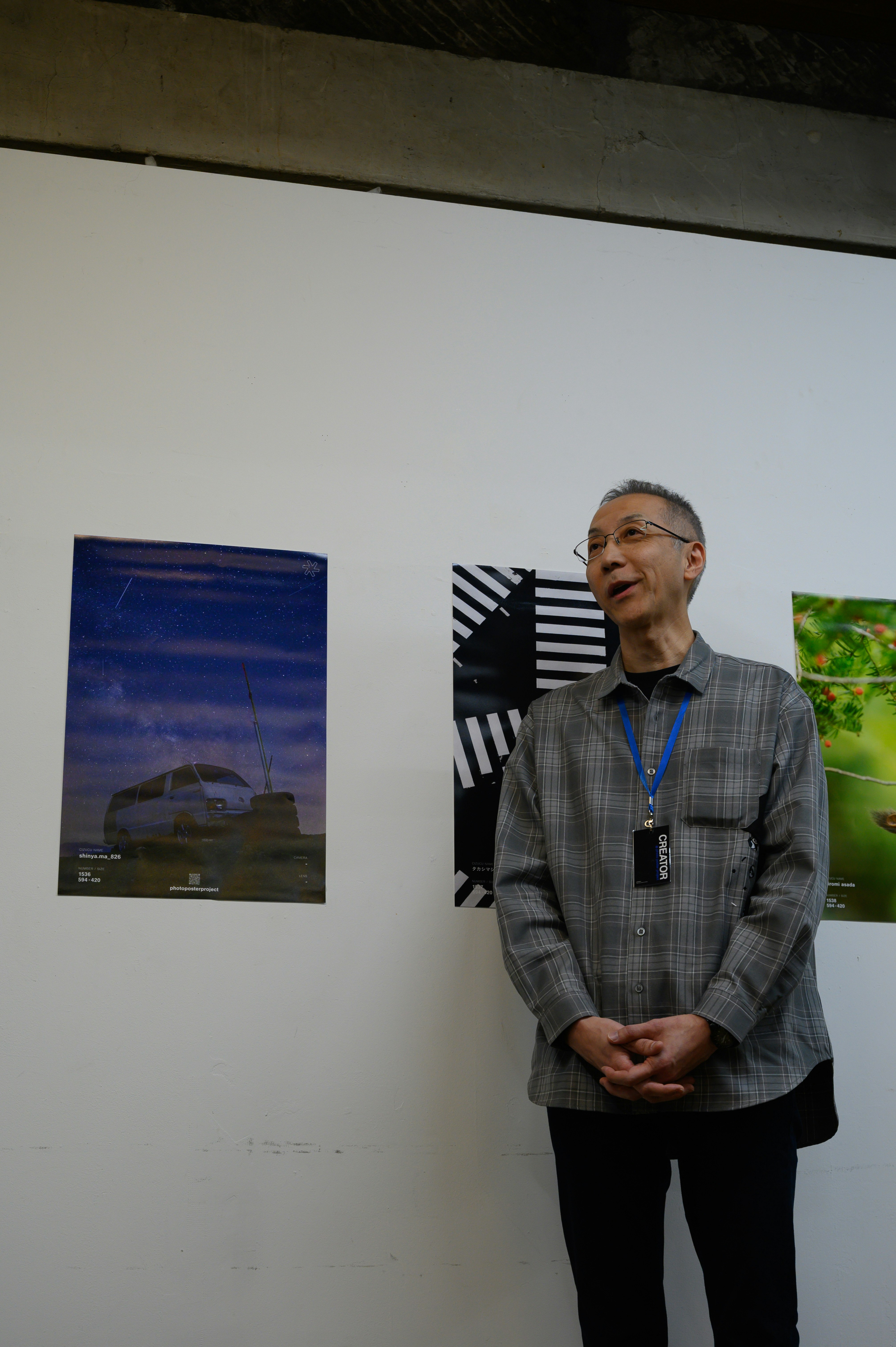 展示会場で立つ男性と壁面のアートパネル