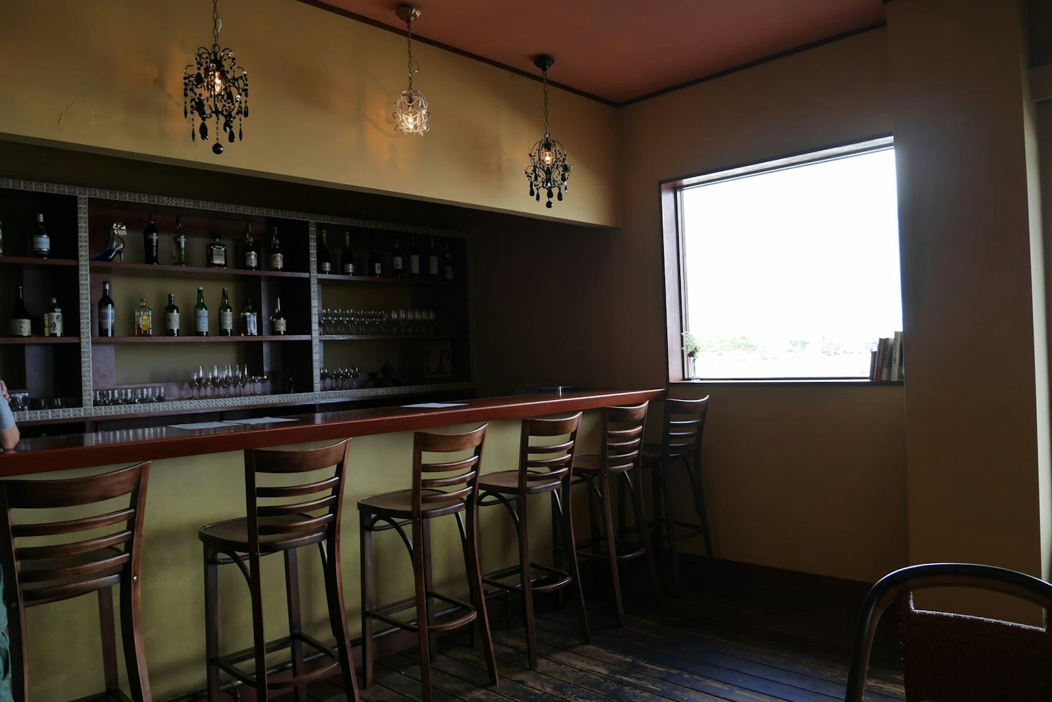 Intérieur d'un bar calme avec des chaises en bois et une étagère illuminée par la lumière d'une fenêtre lumineuse
