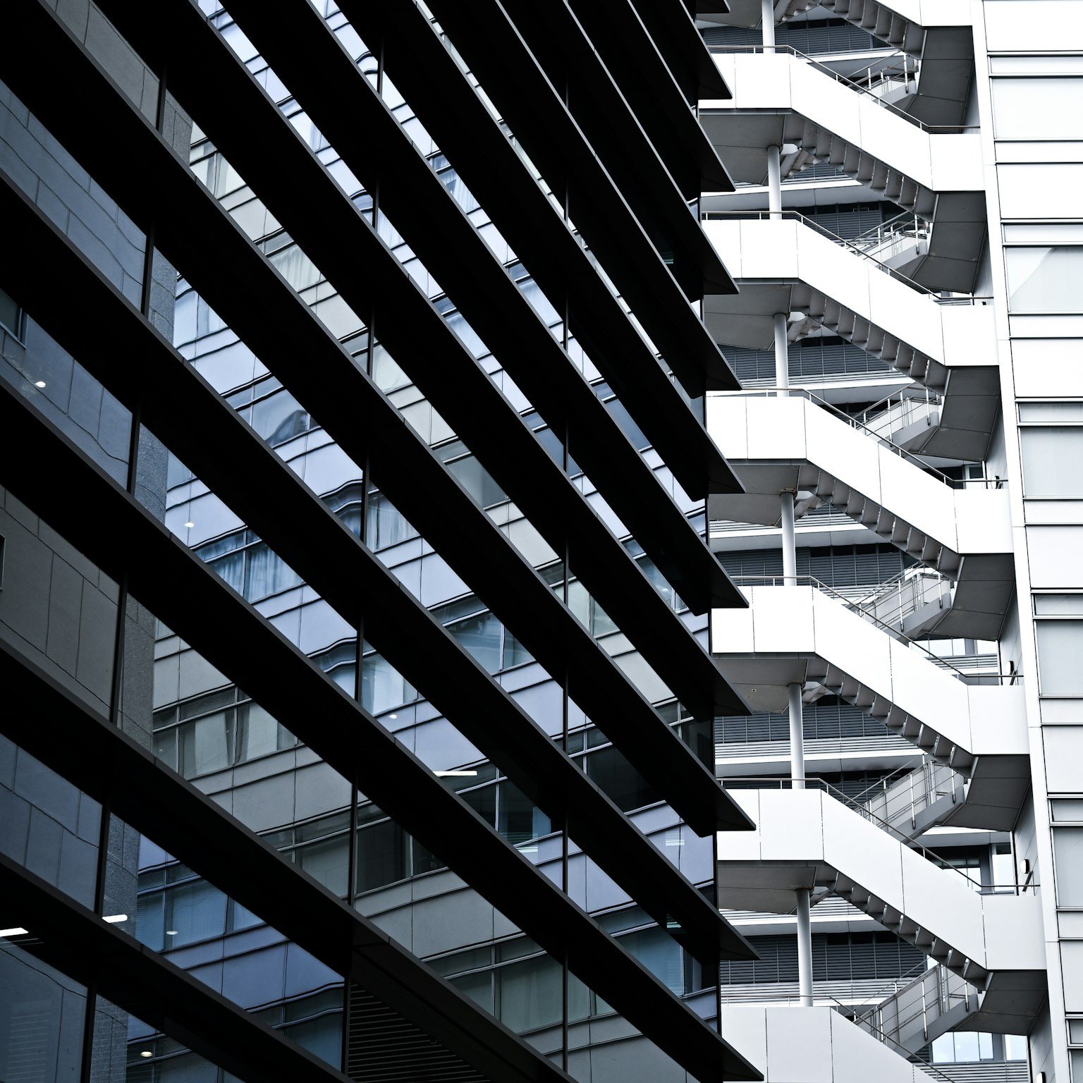 Façade moderne d'immeuble avec des bandes noires et un escalier en colimaçon blanc