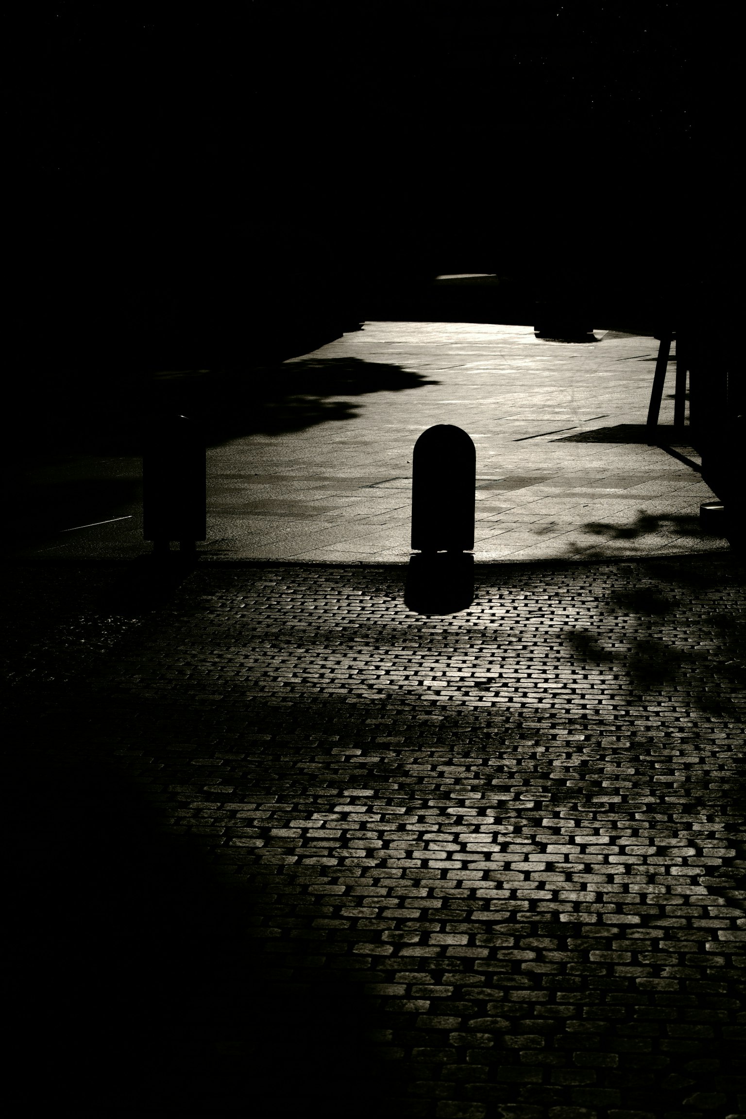 Une rue faiblement éclairée avec un poteau et des reflets de lumière