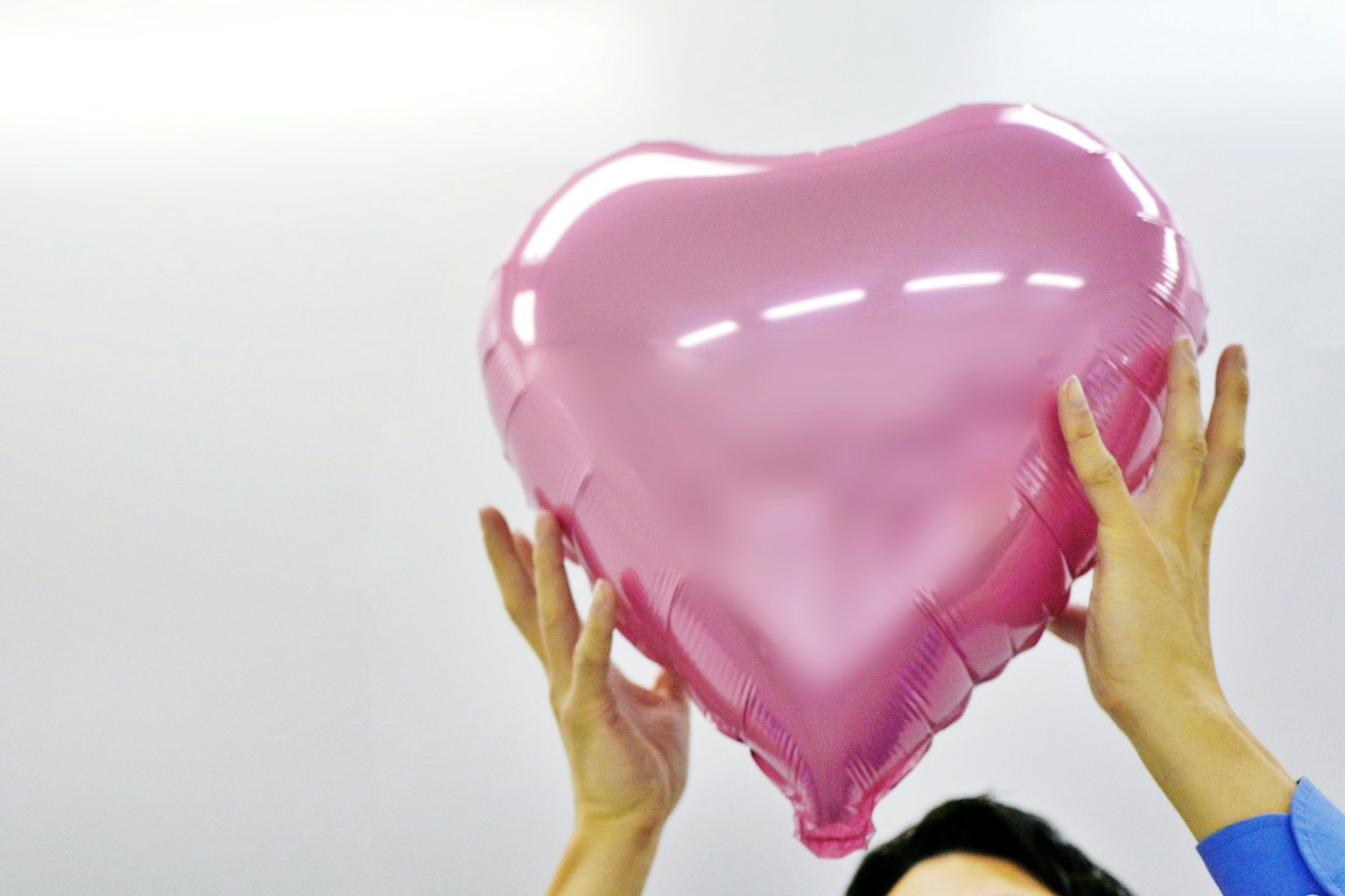 Hände halten einen rosa Herzballon