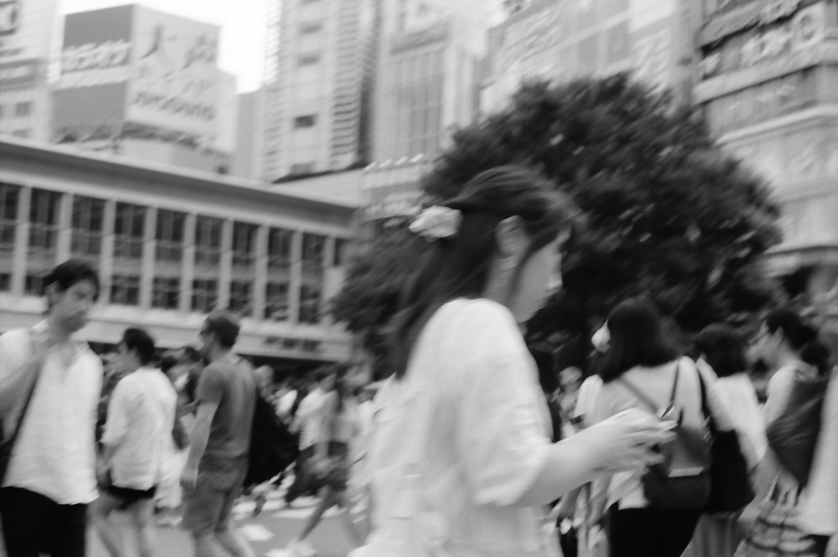 people walking in a city plaza with tall buildings