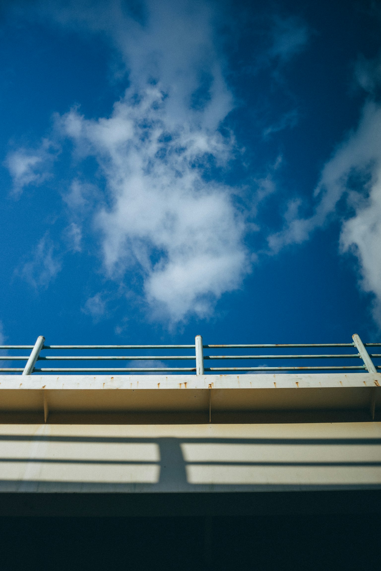 Parte di un ponte sotto un cielo blu con nuvole bianche