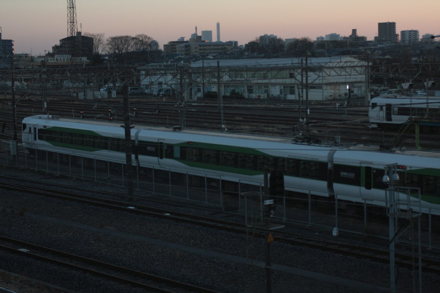 Dusk railway scene featuring green train and tracks