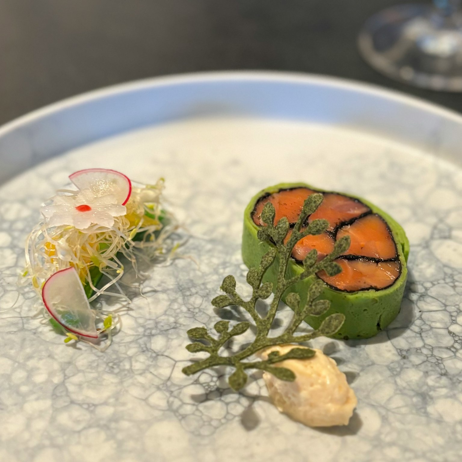 Schön angerichteter Sushi-Teller mit grünem Algenroll und Radieschenblüte