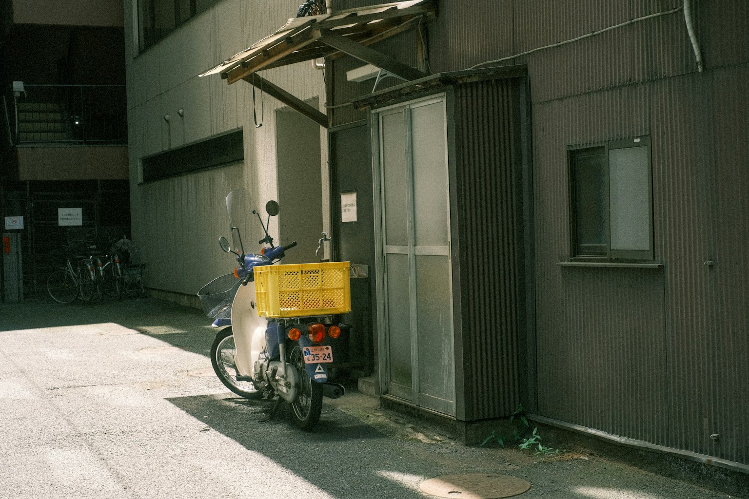 Liefermotorrad mit gelbem Kasten, geparkt in einer engen Gasse neben einem alten Gebäude