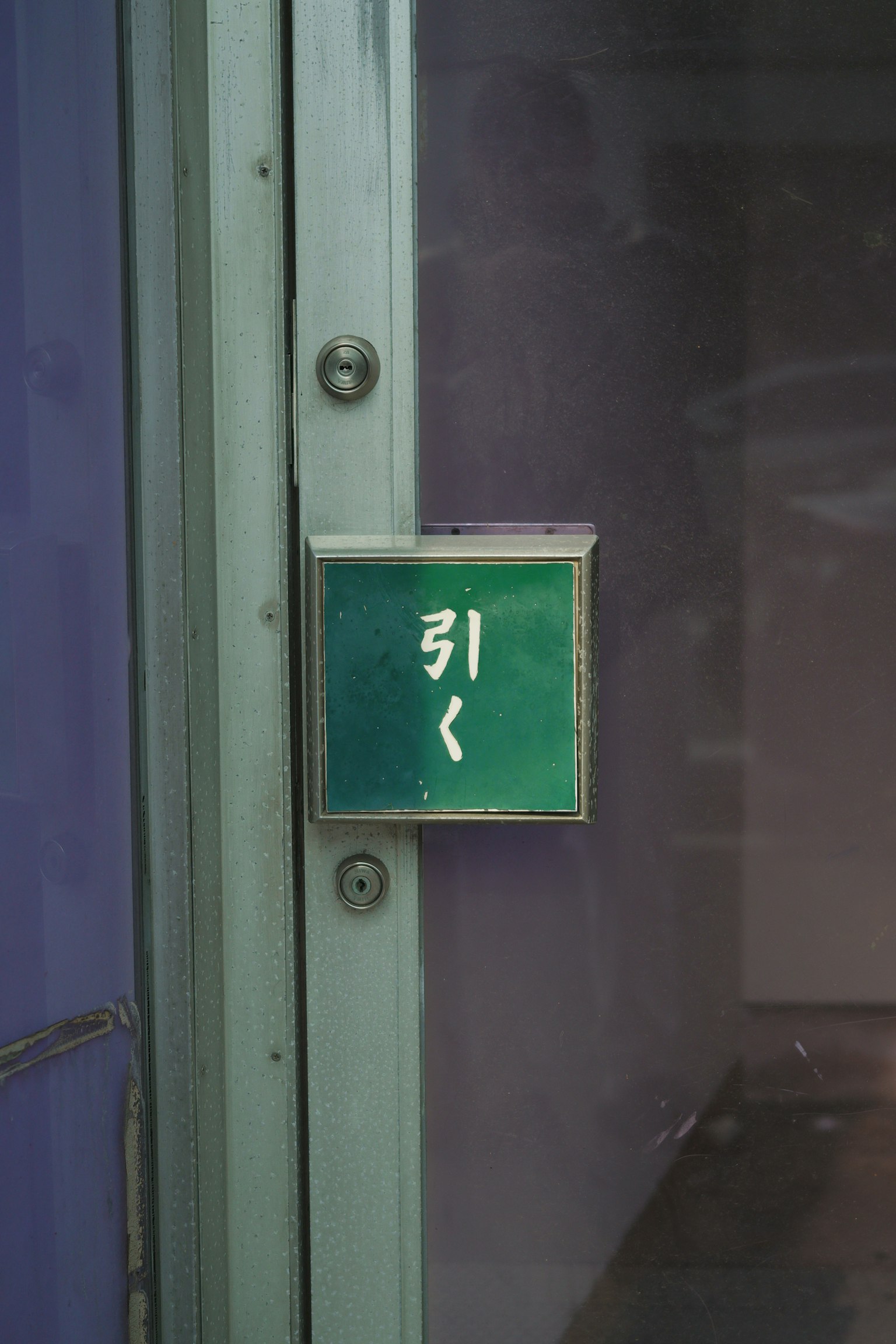 Panneau vert avec le mot '引く' fixé à une porte
