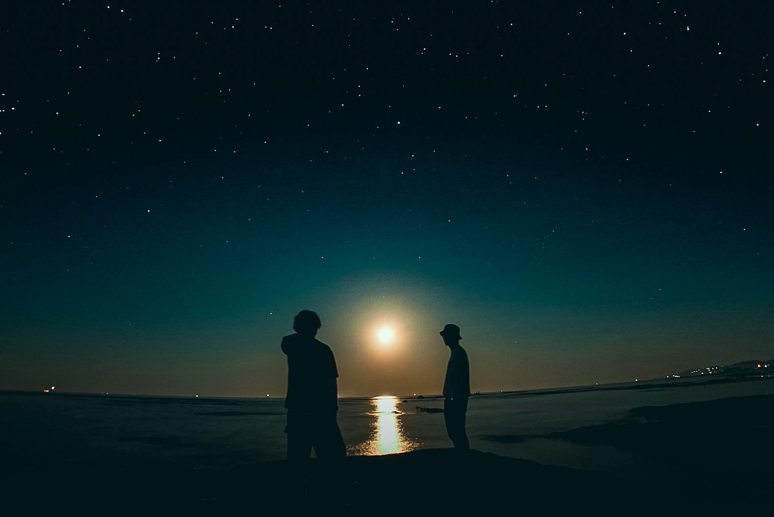 在星空下仰望月亮的两个人的轮廓