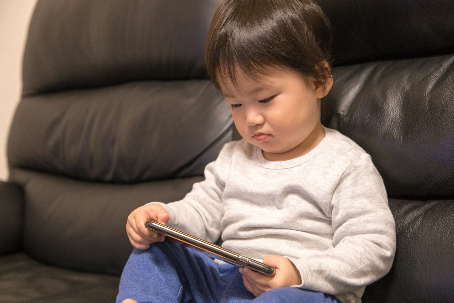 A child sitting on a sofa looking at a tablet