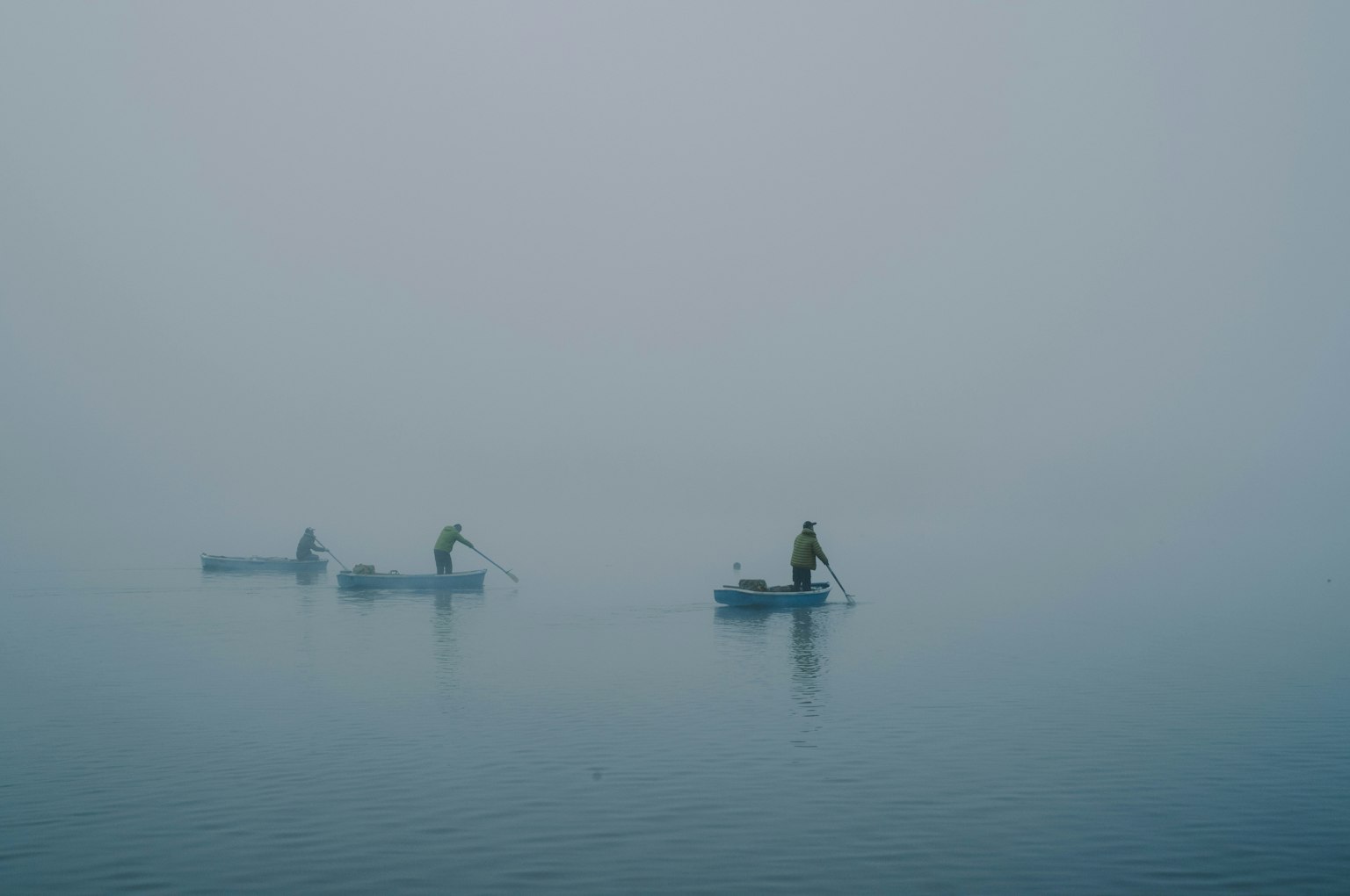 Pescatori in piccole barche nella nebbia