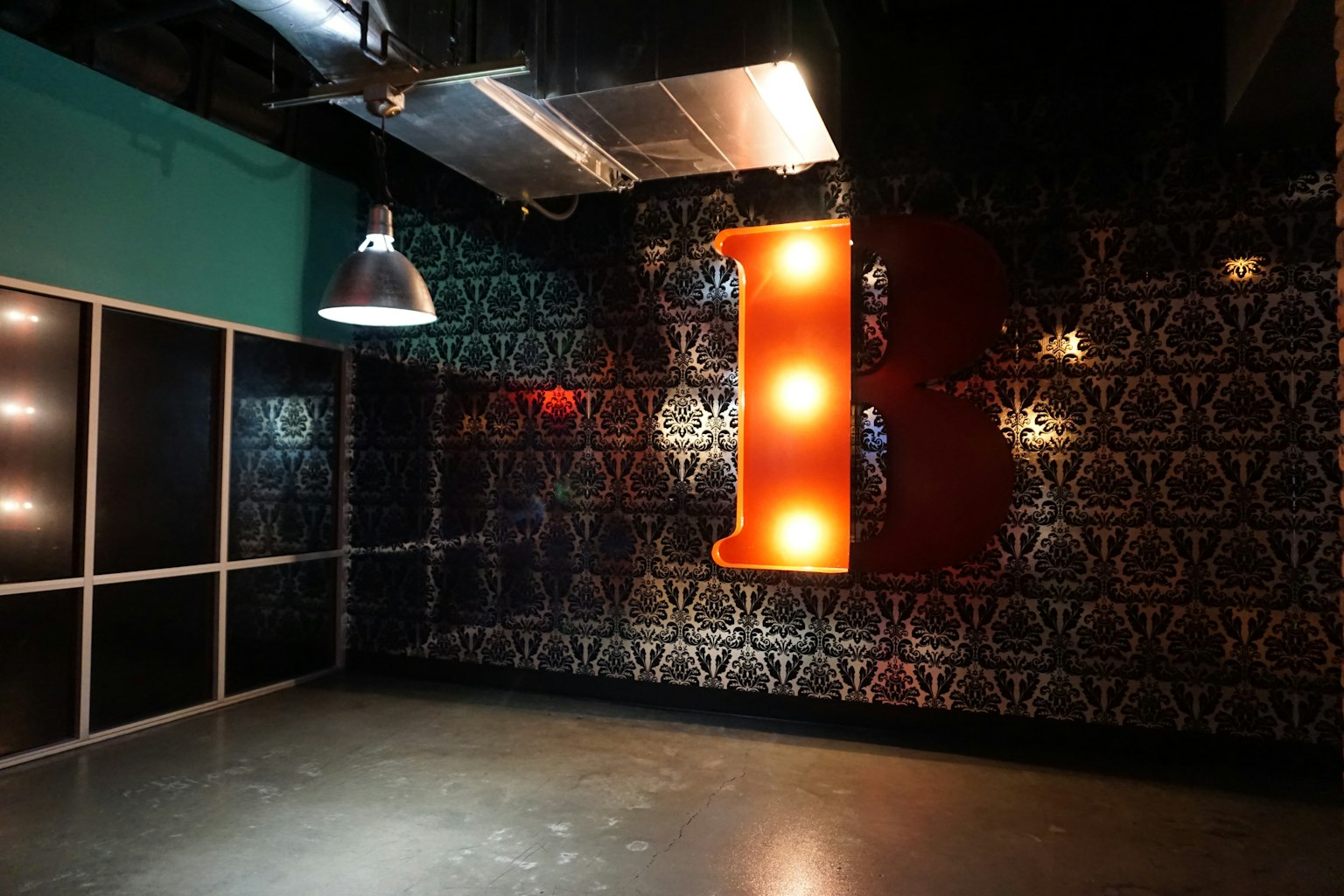 Modernes Interieur mit einem großen beleuchteten orangefarbenen Buchstaben B an einer gemusterten Wand