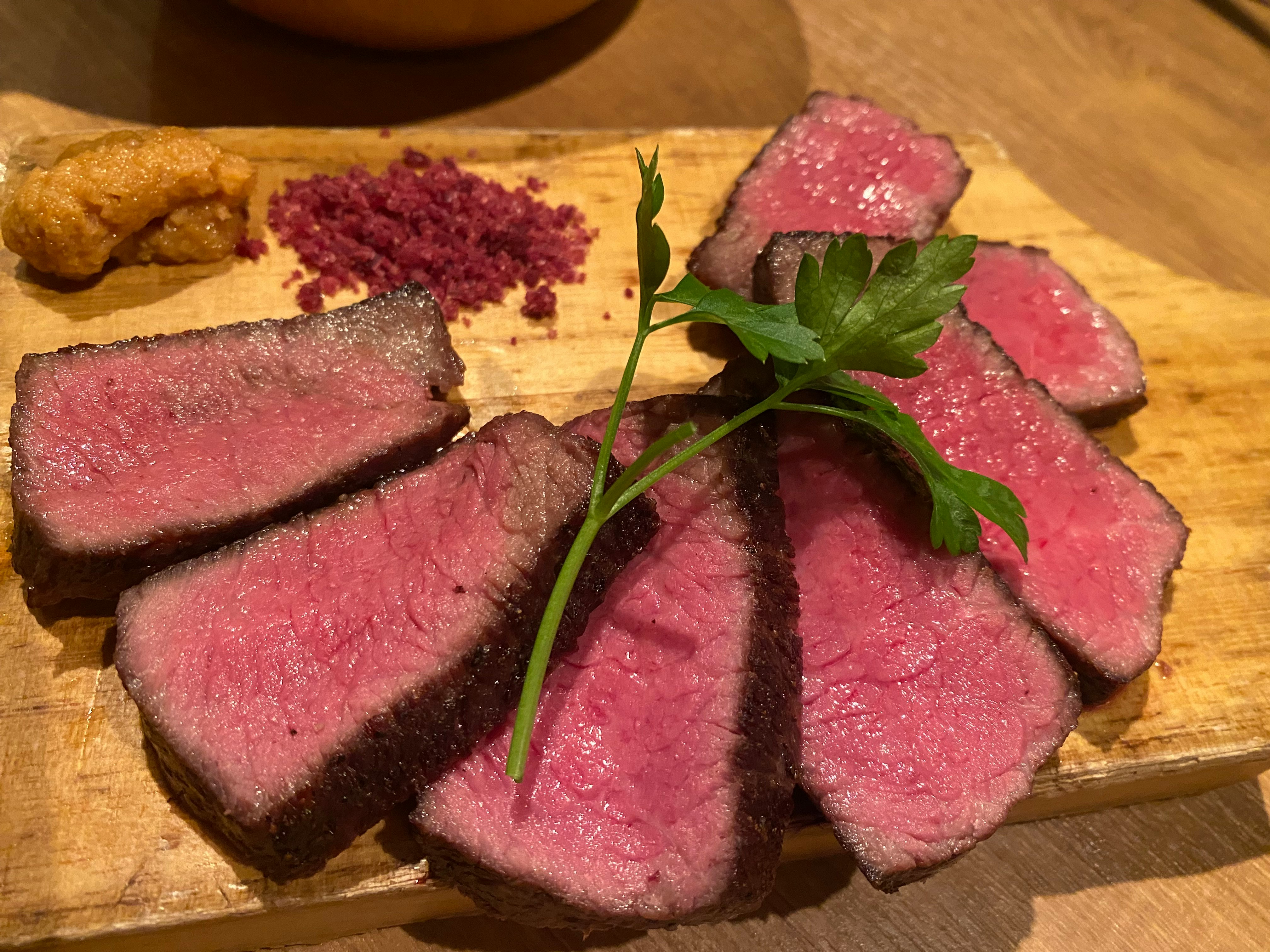 fette di manzo arrosto su un tagliere di legno con erbe fresche