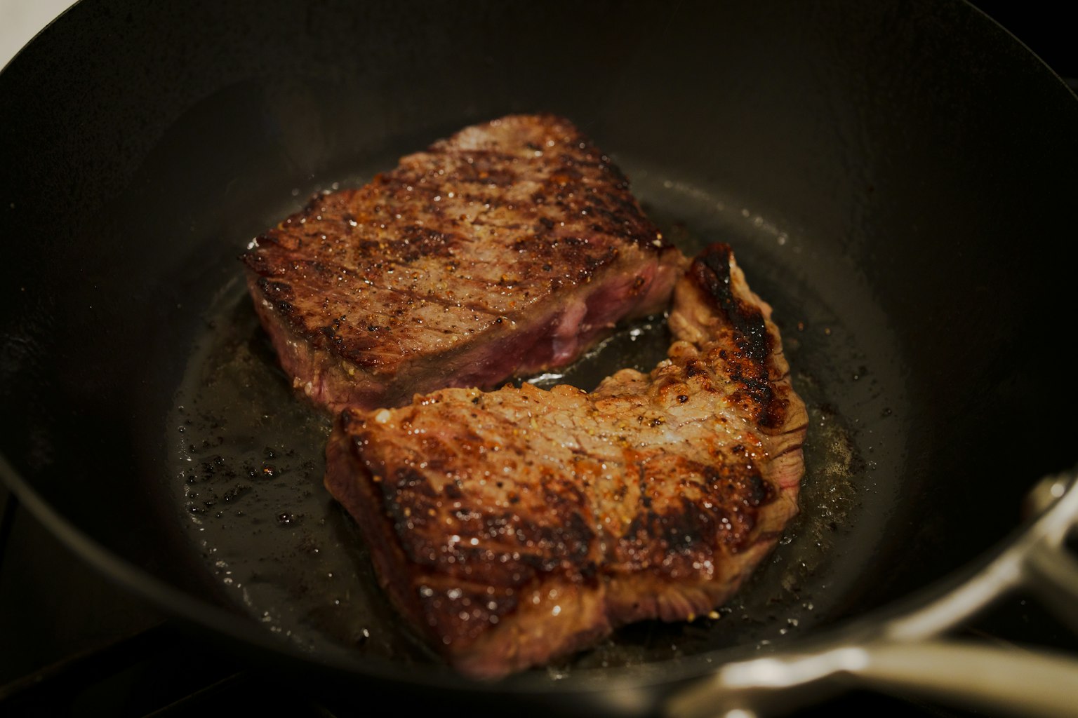 Zwei saftige Steaks brutzeln in einer Pfanne