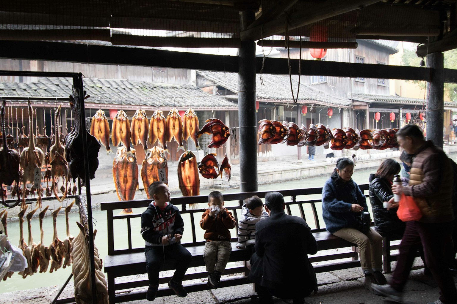 Riverside market stall displaying dried fish with people sitting