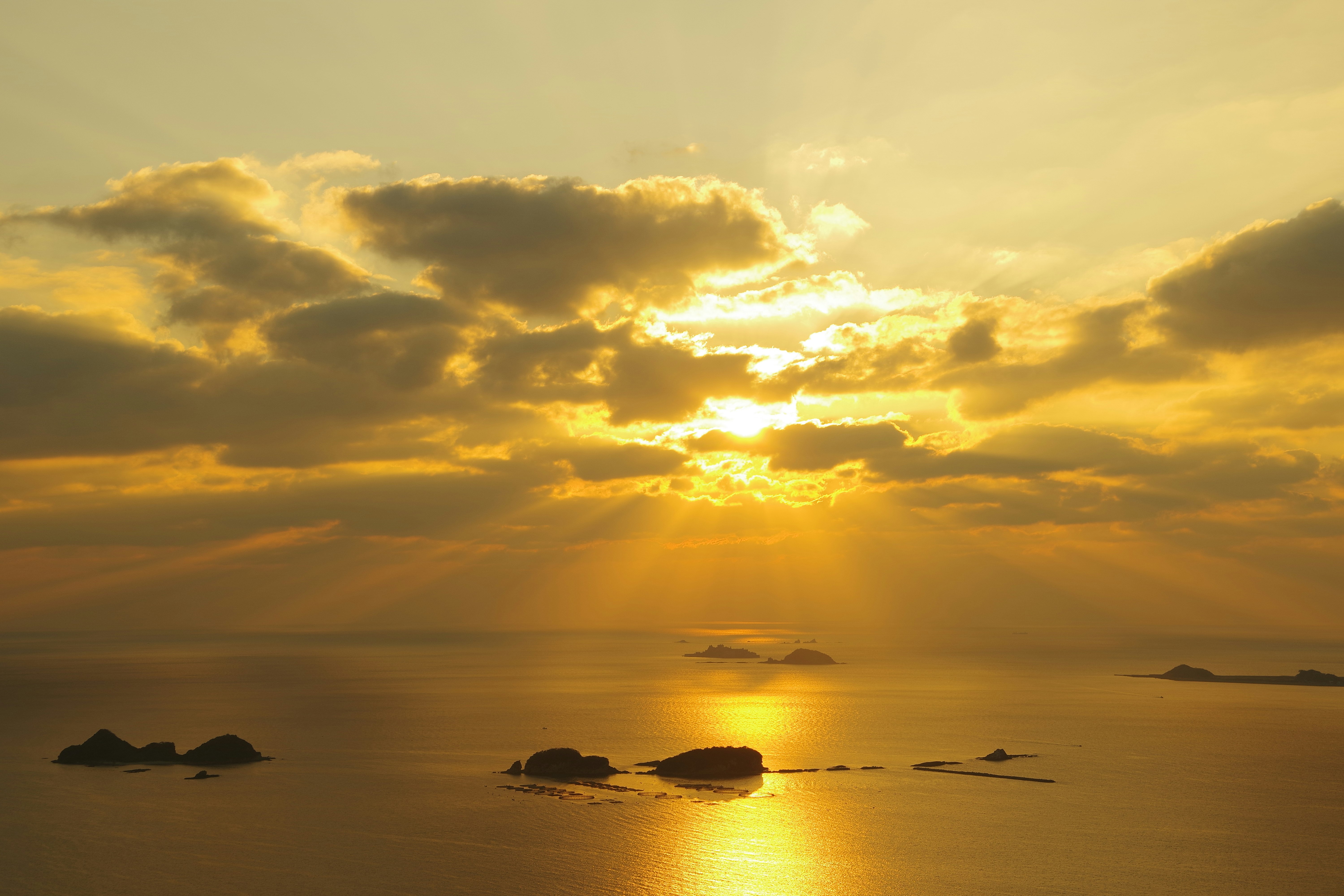 冬空の夕日が海面を照らす薄明光線の風景
