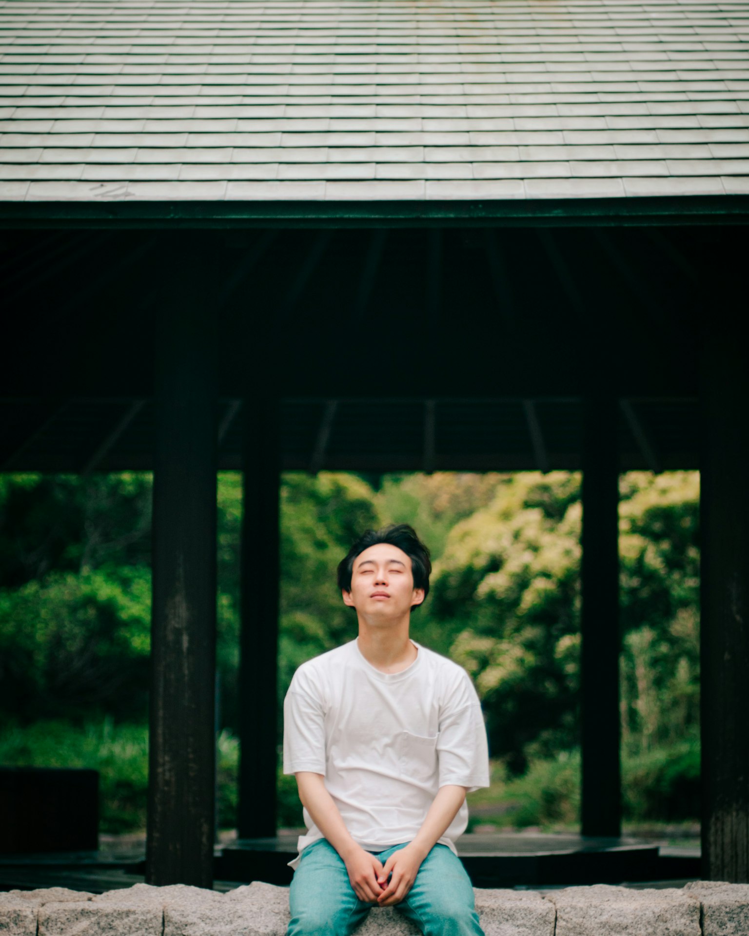 一名穿著白色襯衫和藍色褲子的男人坐在綠色背景中