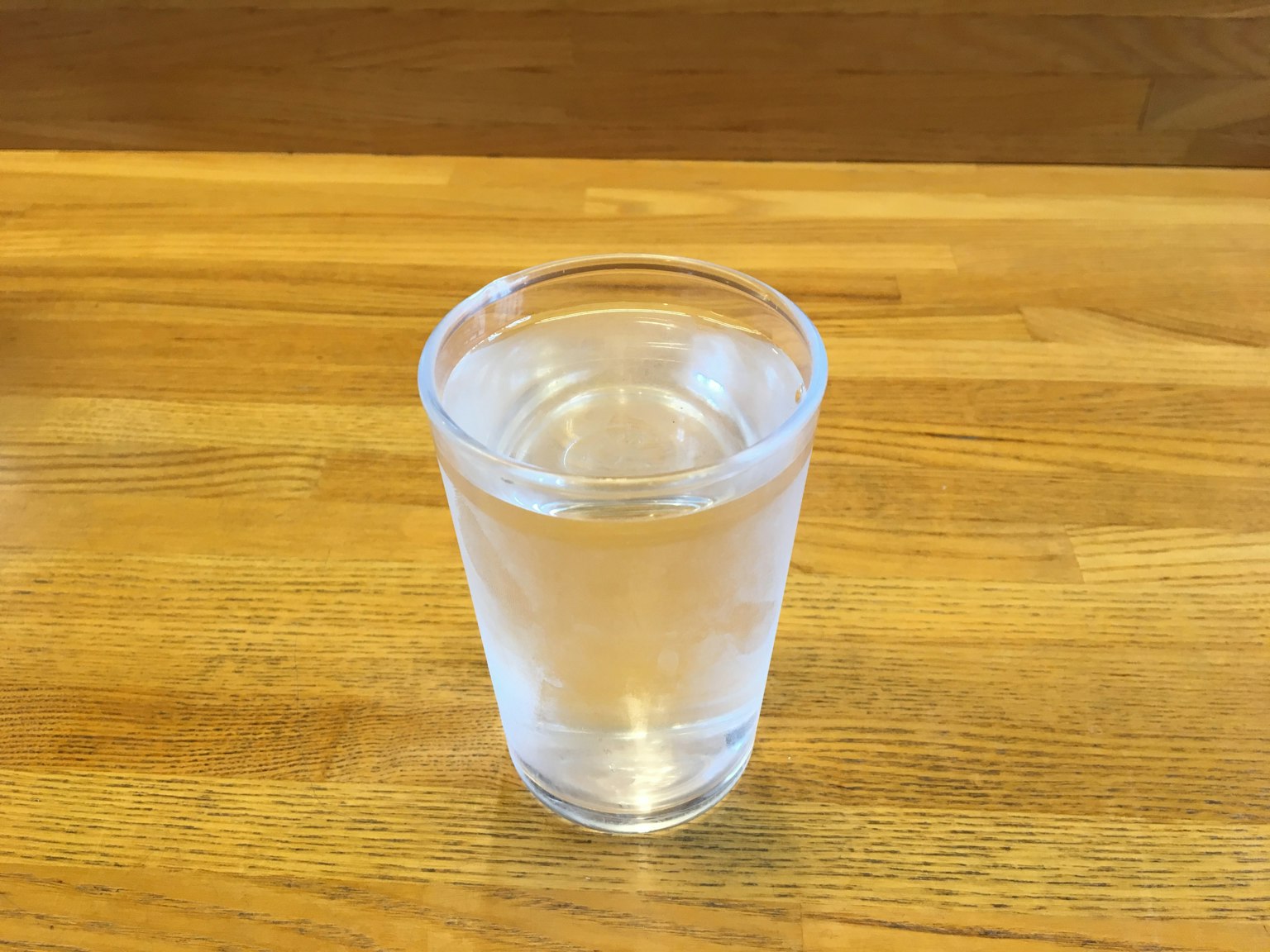 Un bicchiere d'acqua chiara su un tavolo di legno