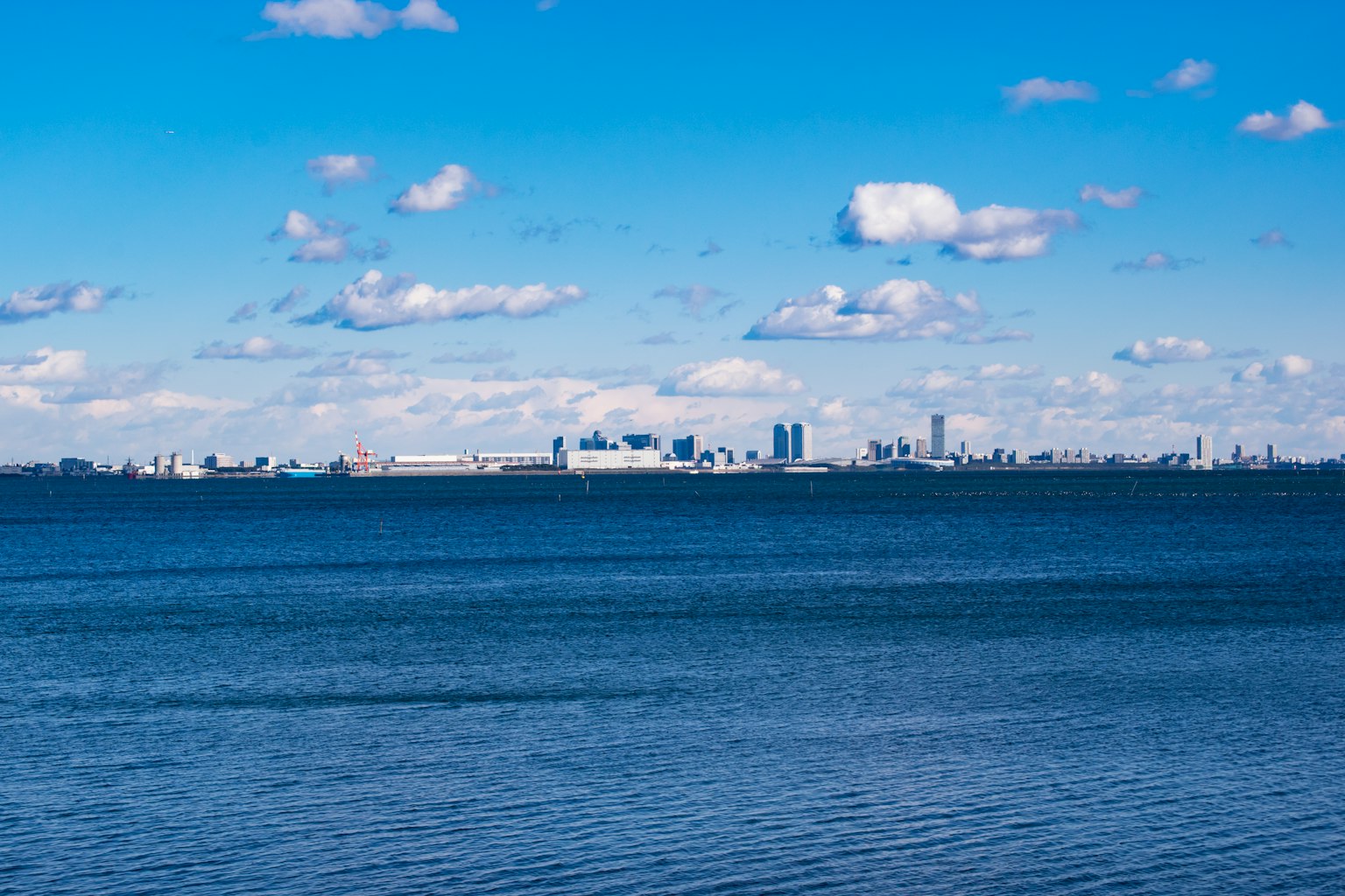 Skyline della città sotto un cielo blu con nuvole sopra una superficie d'acqua calma