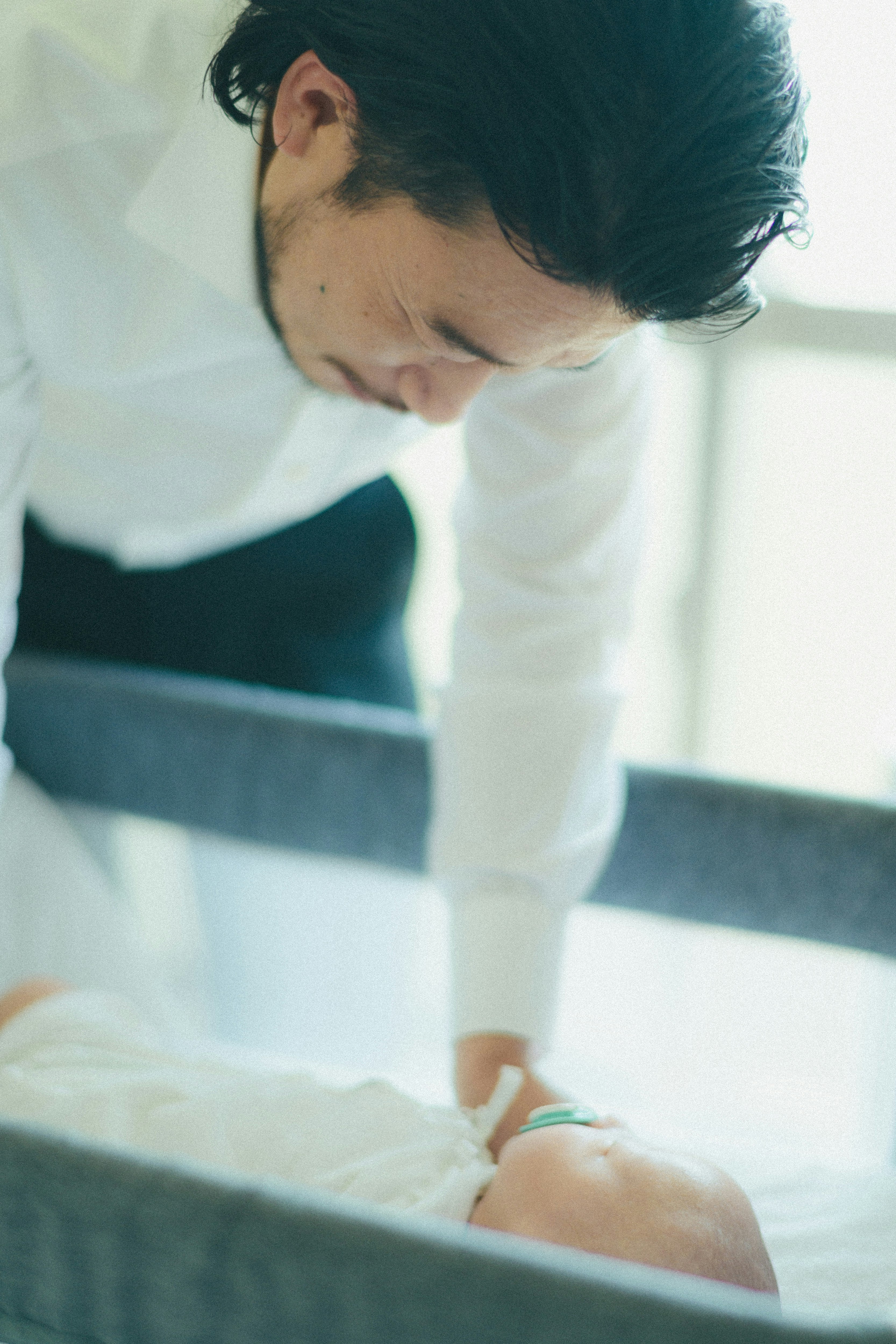 赤ちゃんを見守る男性の優しい表情と白いシャツ
