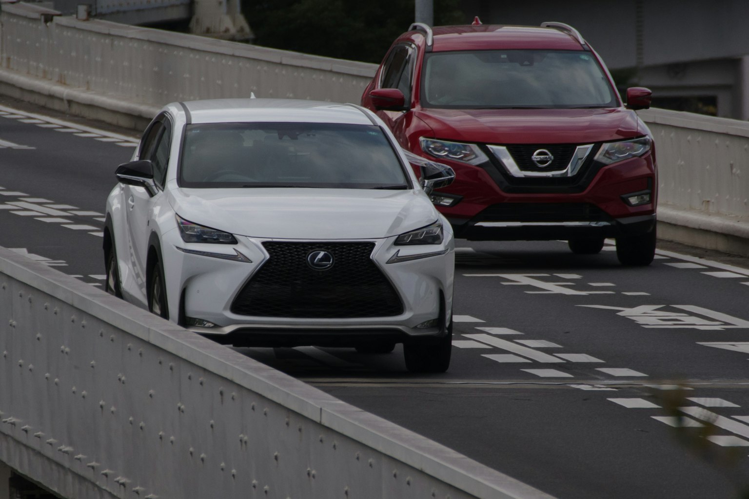 Un SUV blanc Lexus et un SUV rouge Nissan roulant sur une autoroute
