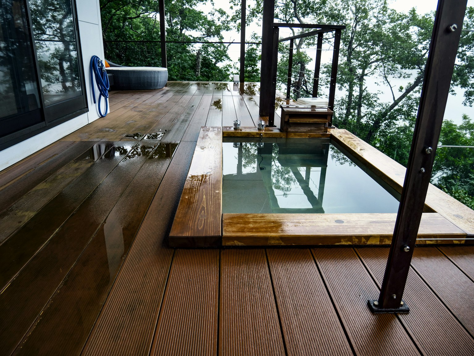 Wooden deck with a small soaking tub and trees in the background