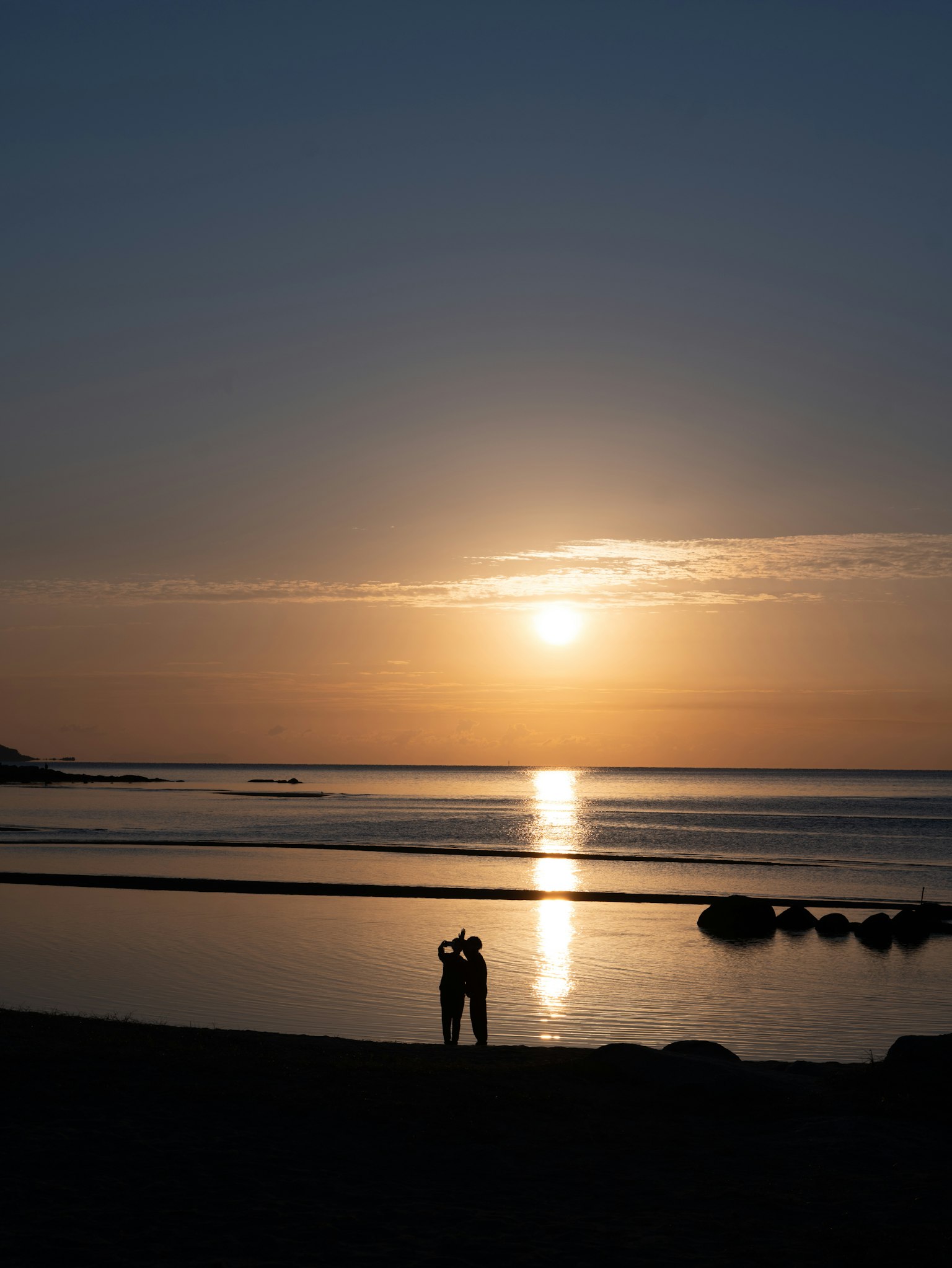 해변에서 일몰을 배경으로 한 커플의 실루엣이 로맨틱한 장면을 연출