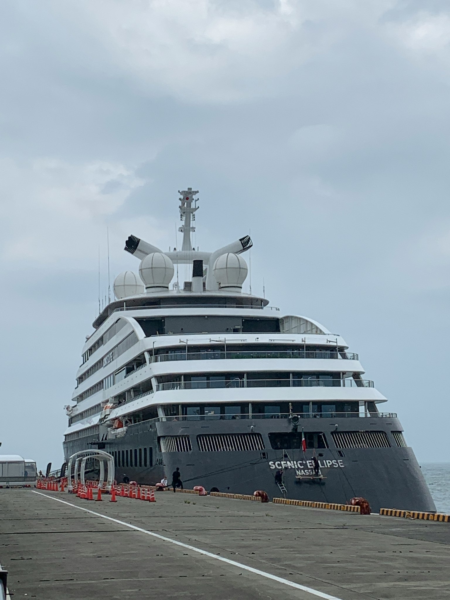 Luxury cruise ship docked at the port with a cloudy sky
