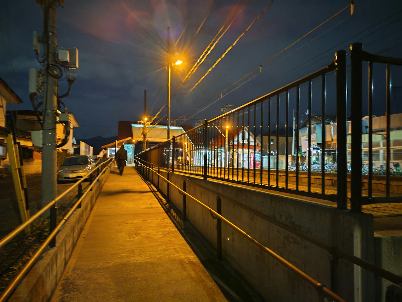 Una persona che cammina su un marciapiede di notte con lampioni