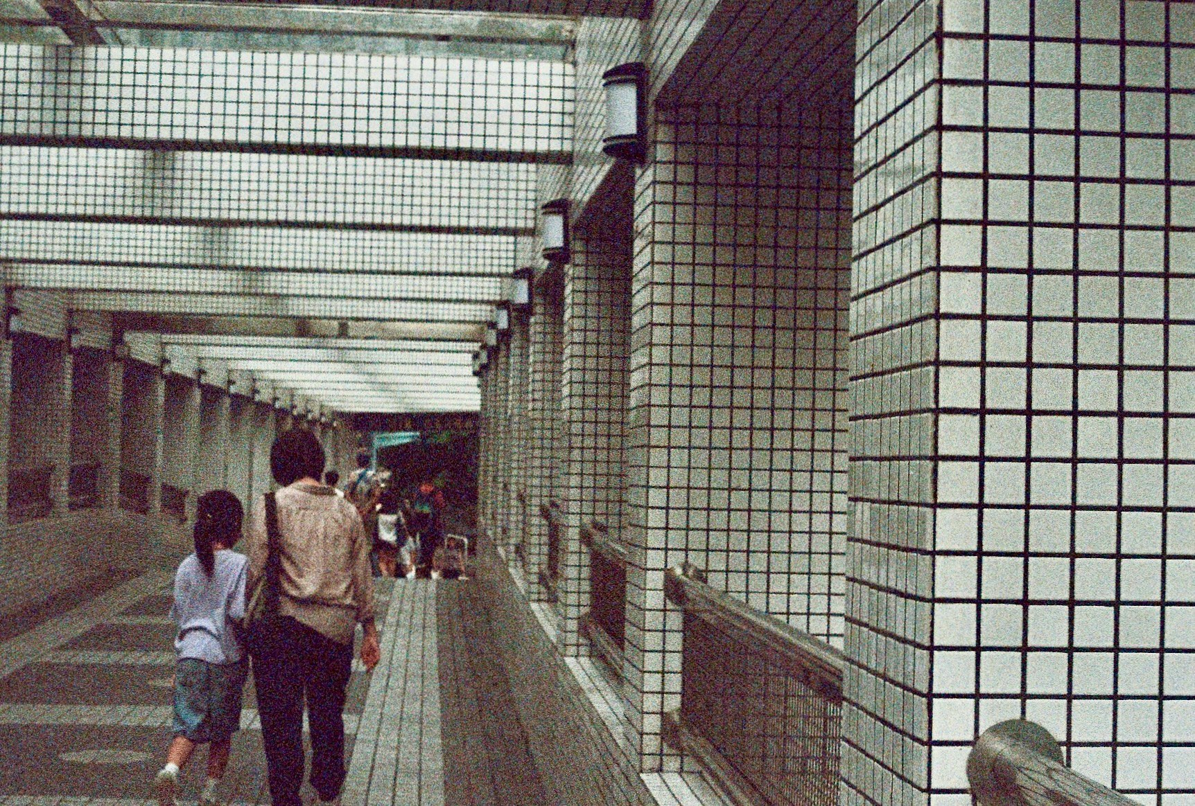 タイル張りの通路を歩く人々のある駅構内の風景