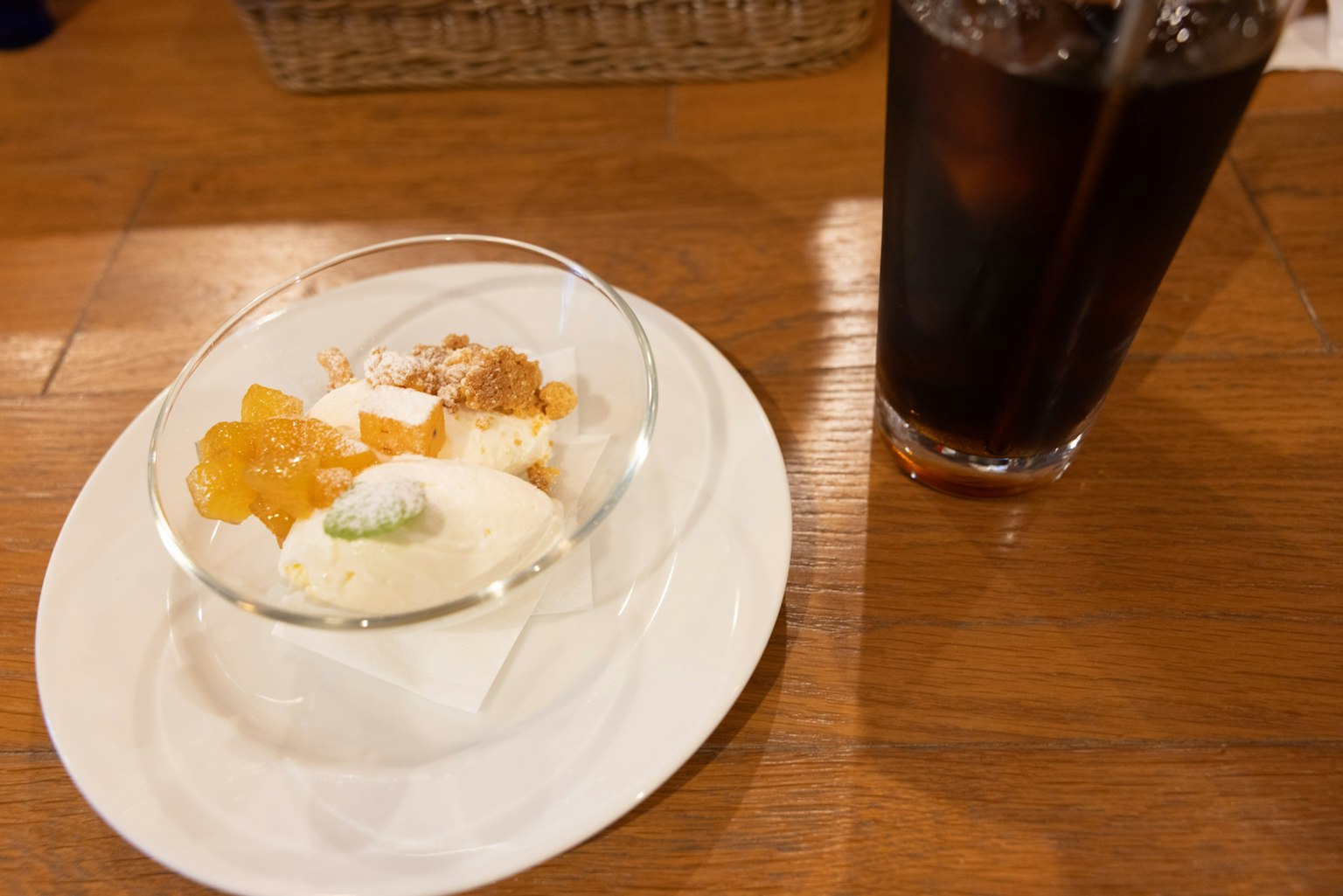 Ein Dessertteller mit Eis und Obst neben einem Glas Cola