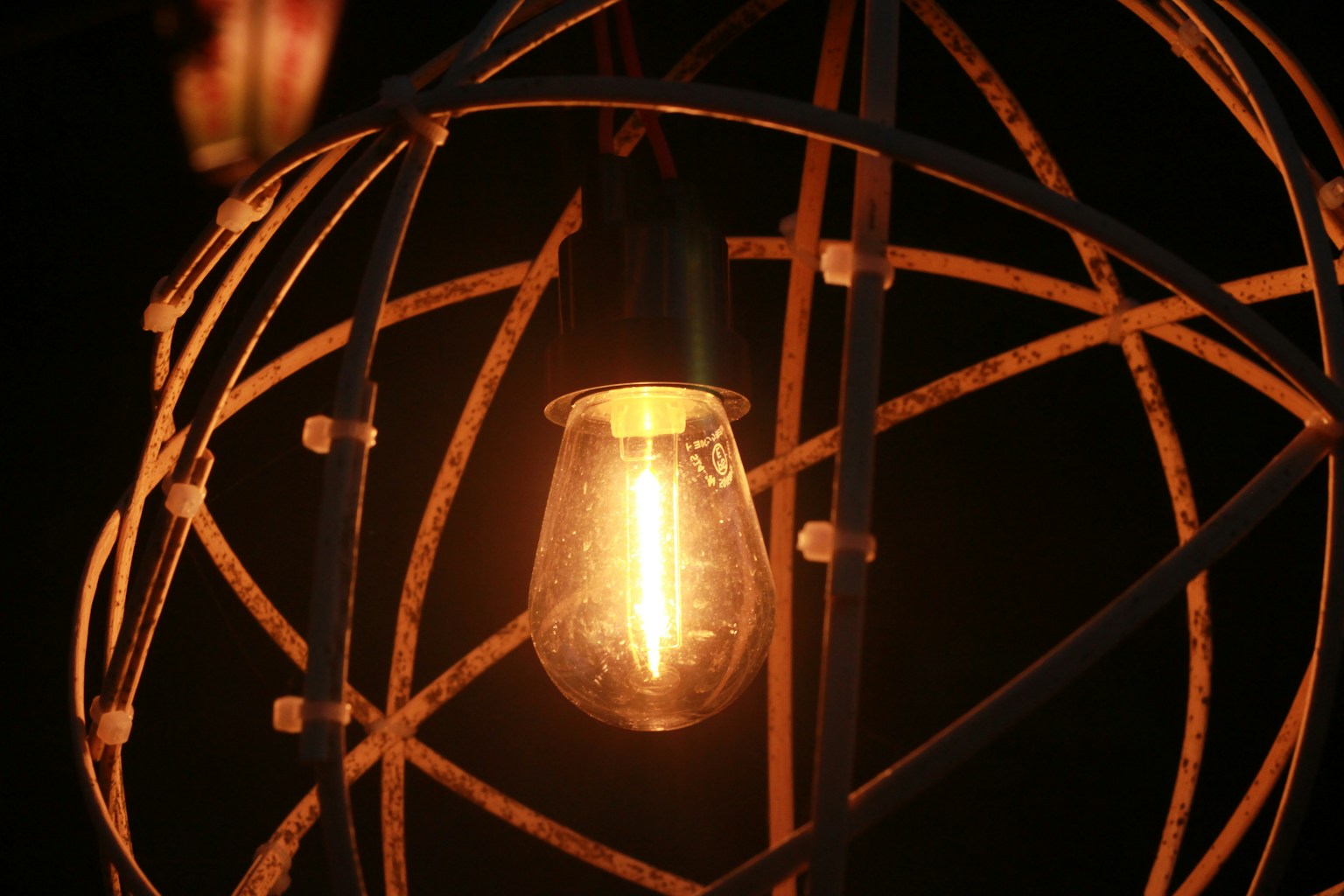 Una bombilla brillante rodeada de un marco metálico decorativo