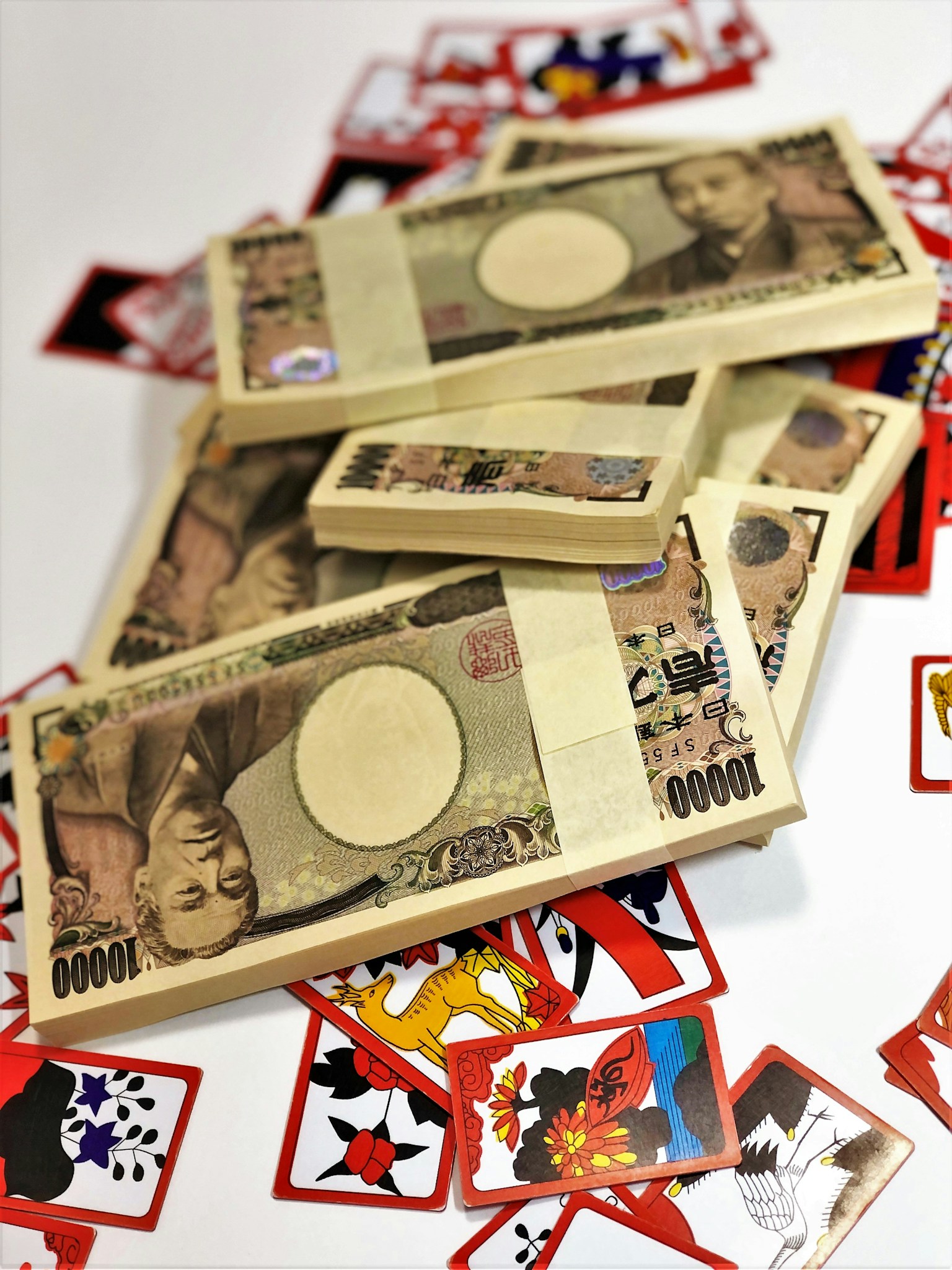Một chồng yên Nhật Bản được bao quanh bởi các thẻ Hanafuda rải rác