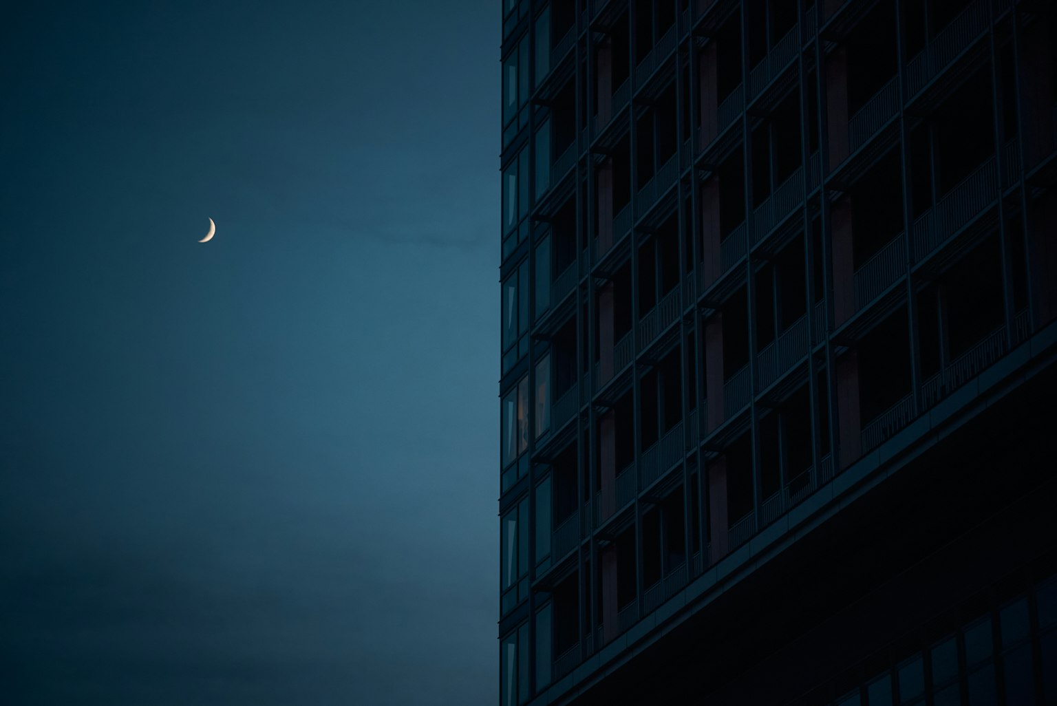 Luna crescente in un cielo scuro accanto a un angolo di edificio
