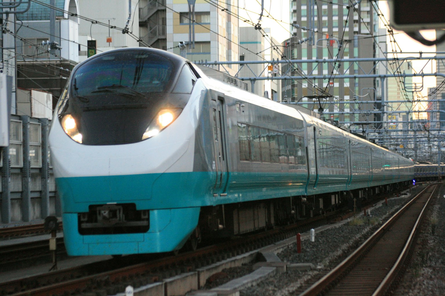 Ein blauer und weißer Shinkansen-Zug, der durch eine städtische Umgebung fährt