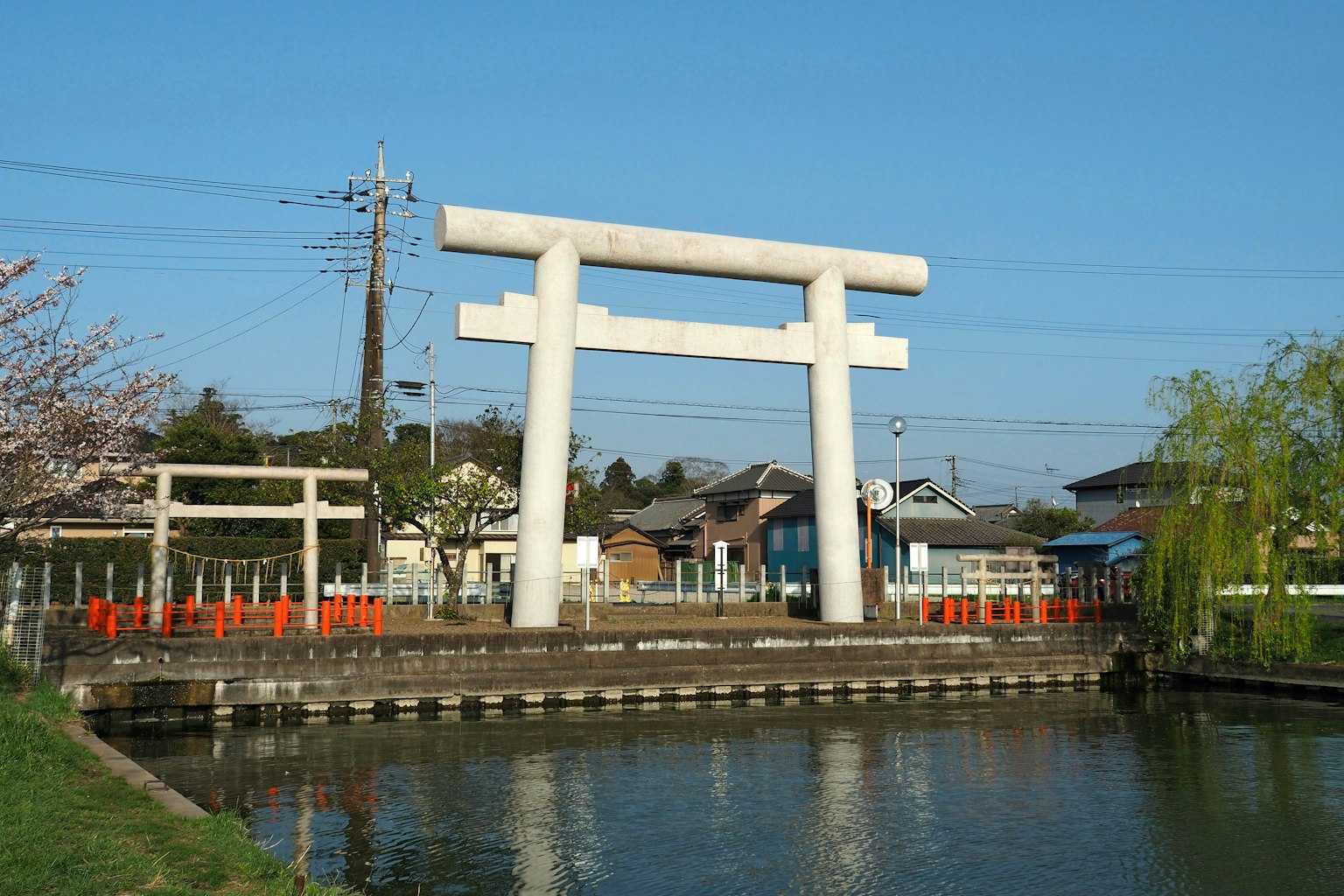 Large white torii gate near a pond under a blue sky