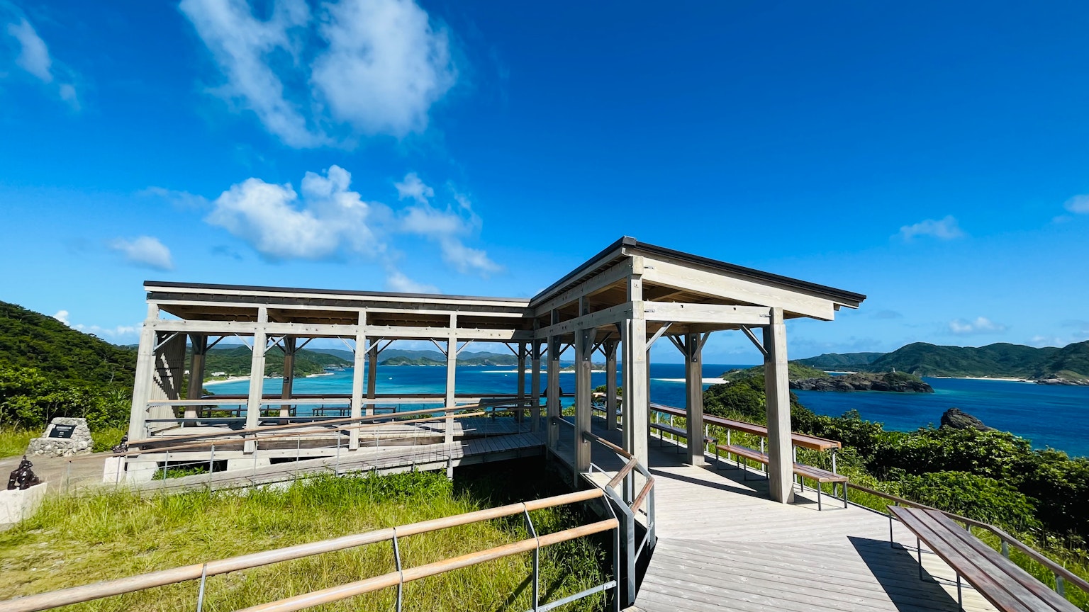 Holz-Aussichtsplattform unter blauem Himmel mit umliegender grüner Landschaft