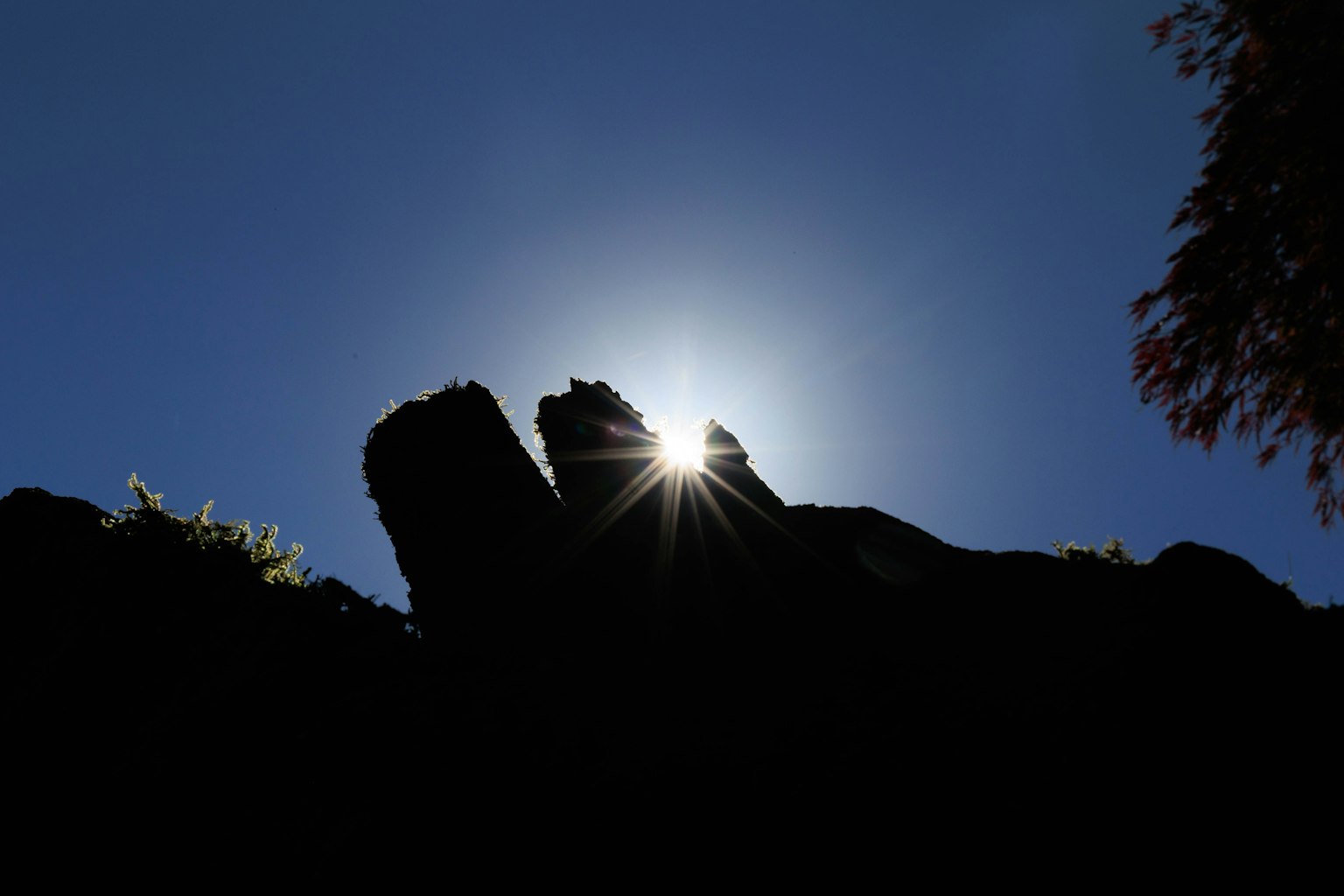 Silhouette of rocks against a bright sky with sunlight