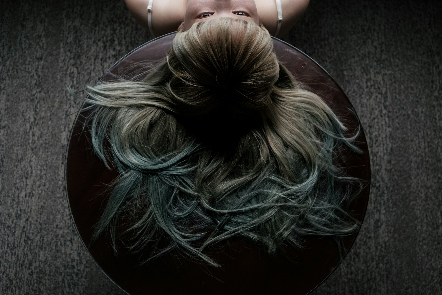 Tampilan atas orang dengan rambut panjang dan sorotan biru duduk di permukaan bulat