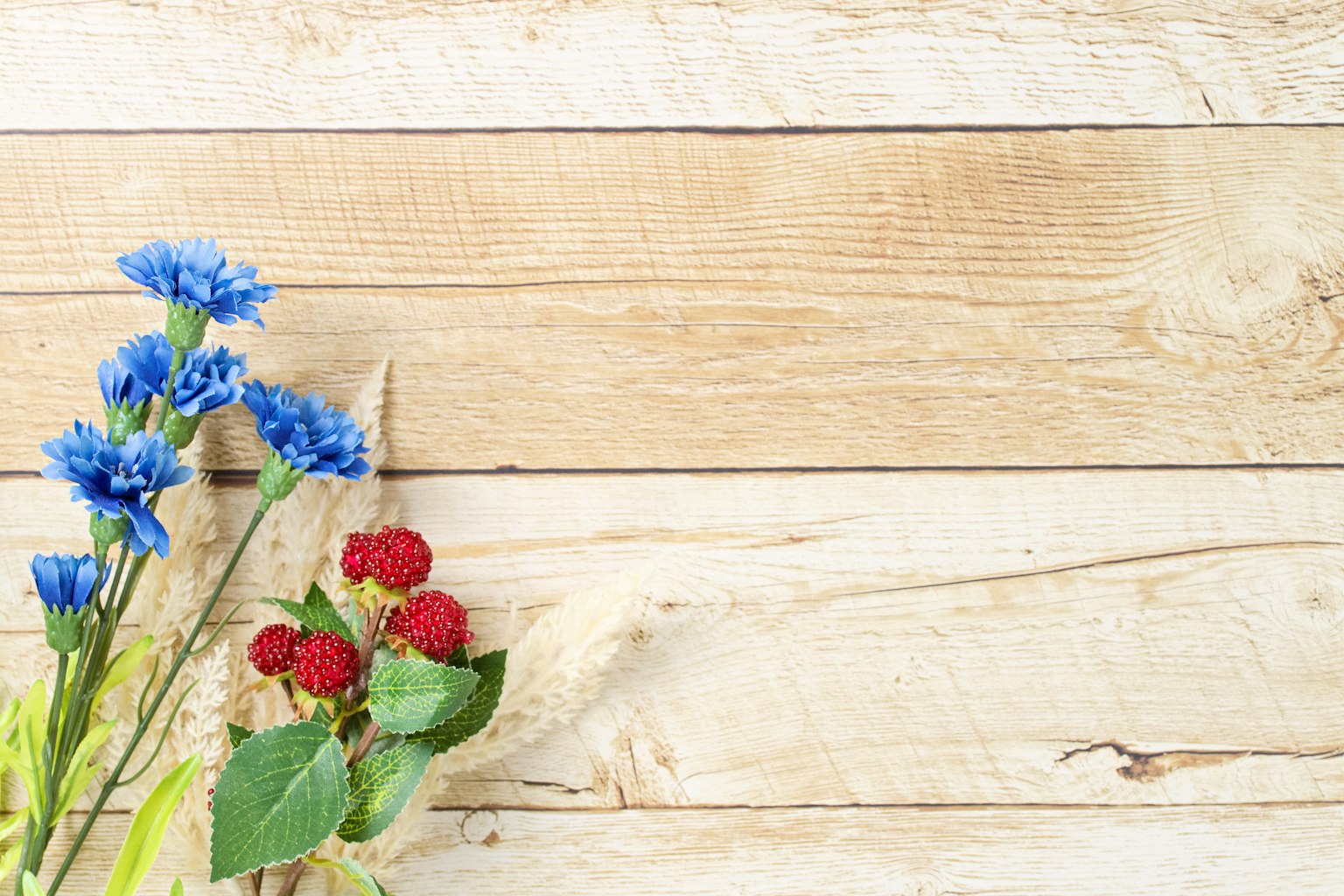 ดอกไม้สีน้ำเงินและผลเบอร์รี่สีแดงจัดเรียงบนแผ่นไม้