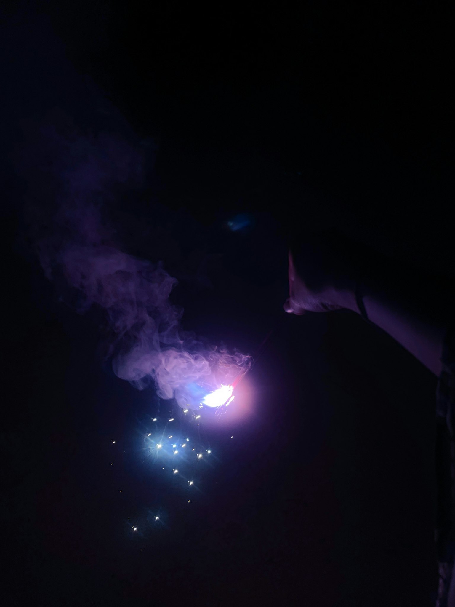 Mano che emette effetti di fumo e luce viola e blu nell'oscurità
