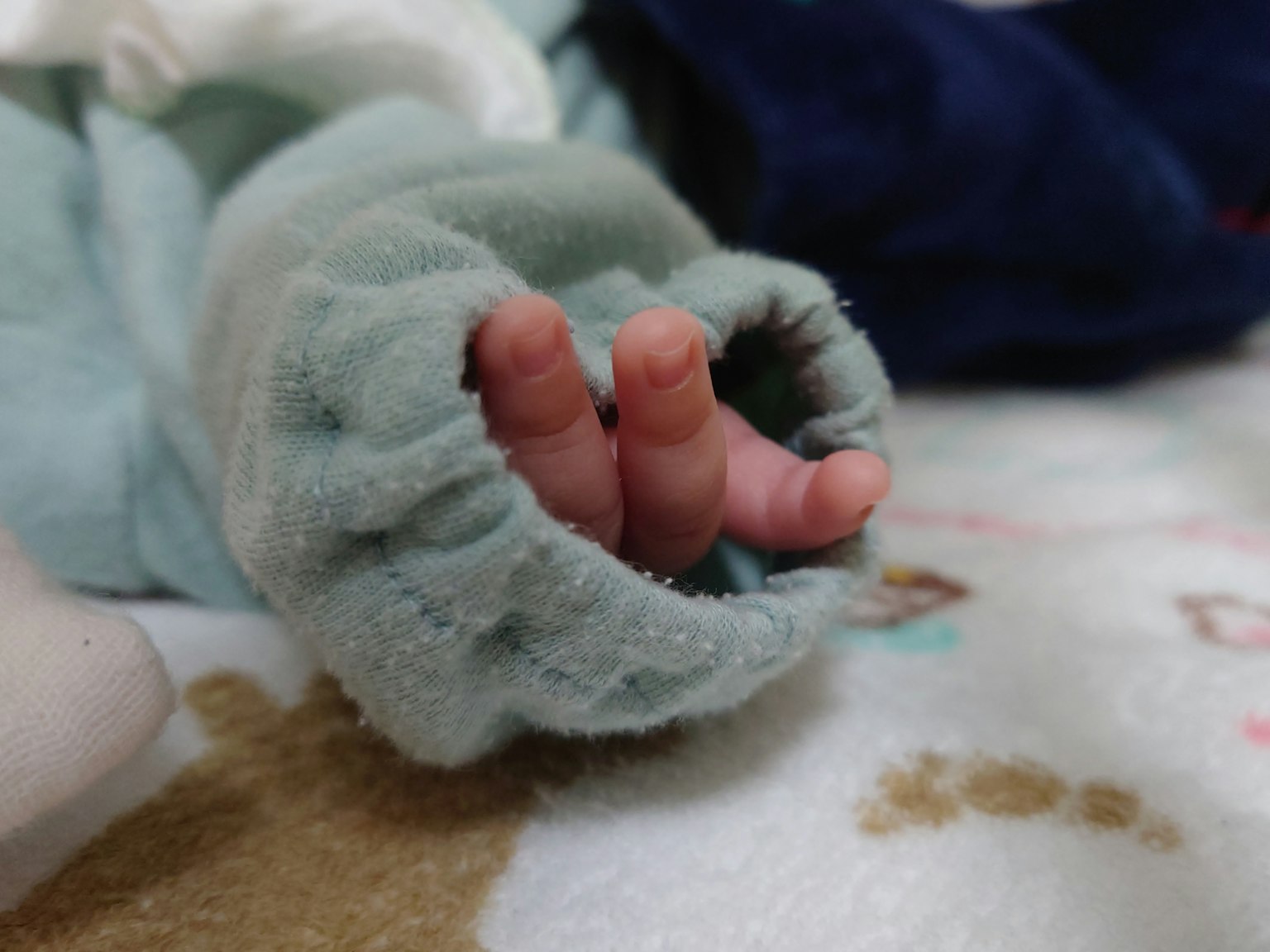 Una pequeña mano de bebé que sale de una suave manga azul
