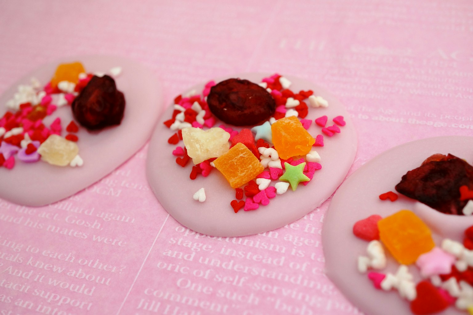 Weißes Bonbon mit bunten Streuseln auf einem rosa Hintergrund