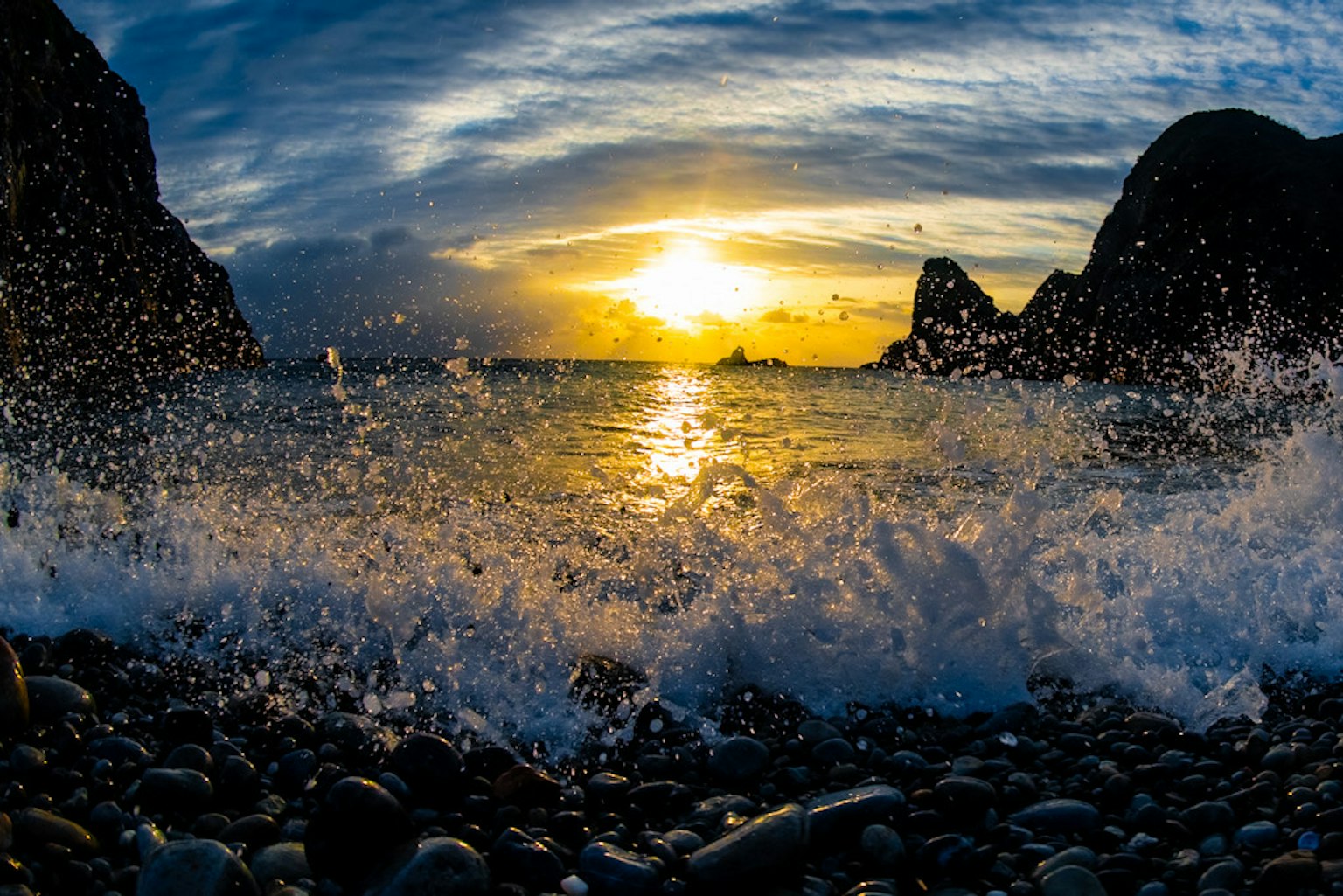 Onde che si infrangono su una spiaggia di rocce al tramonto