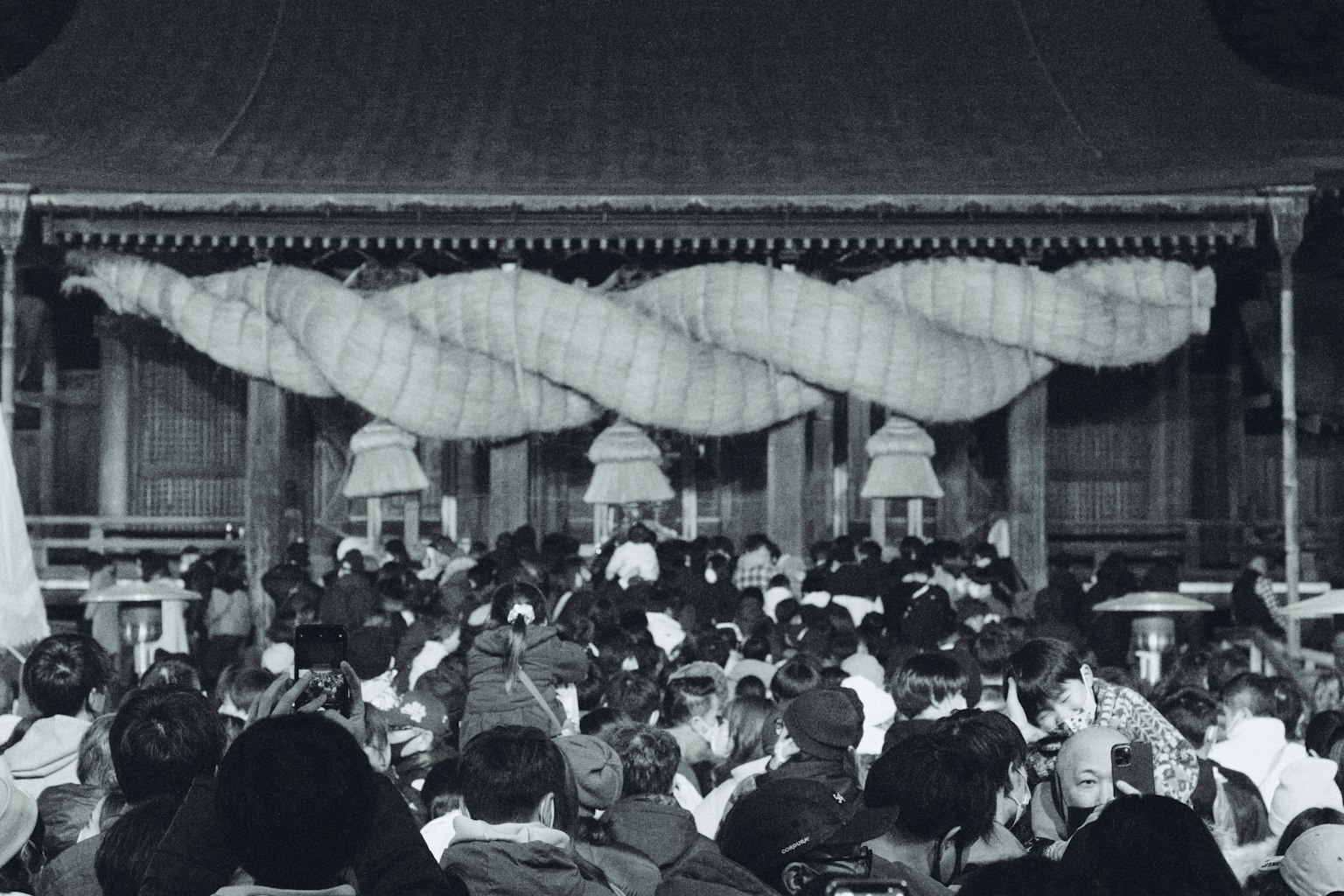 Foule rassemblée lors d'un festival traditionnel avec un bâtiment décoré en arrière-plan