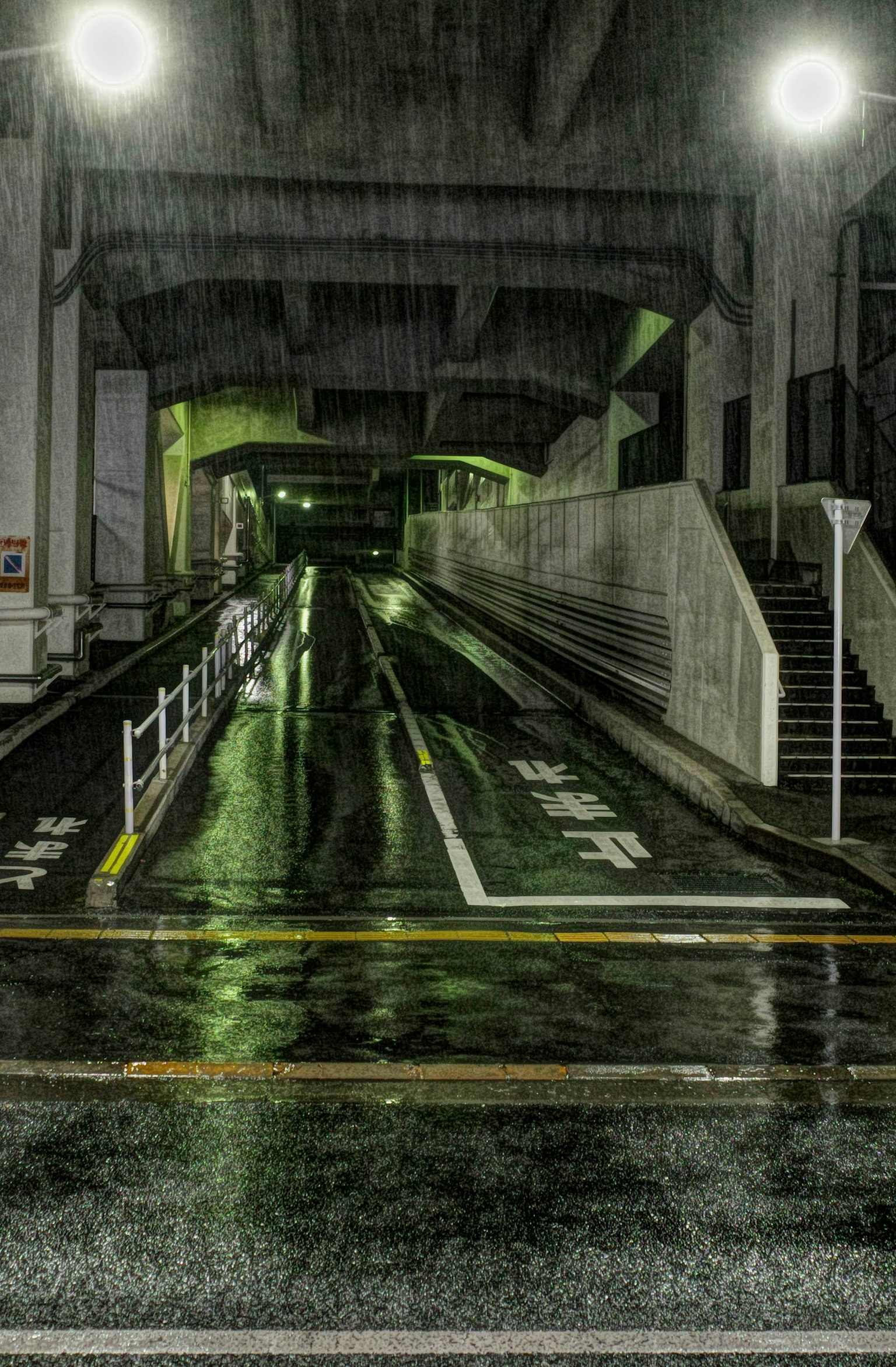 雨の中の暗い道路と照明のあるトンネルの景色