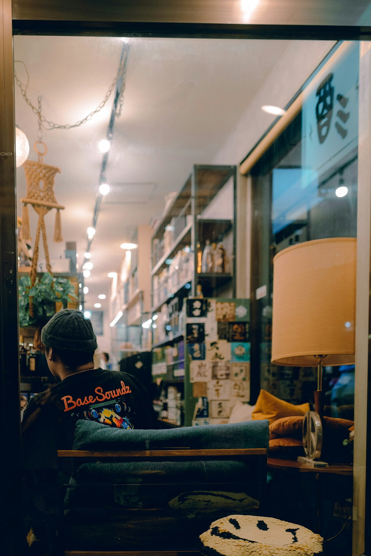 ภายในร้านกาแฟที่อบอุ่นพร้อมคนที่นั่งพักผ่อนอยู่ท่ามกลางชั้นหนังสือและโคมไฟ