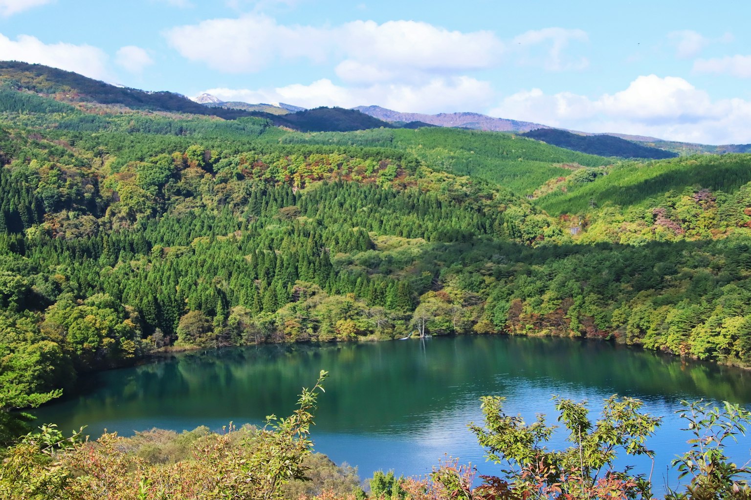 Ruhiger See umgeben von üppigen grünen Bergen