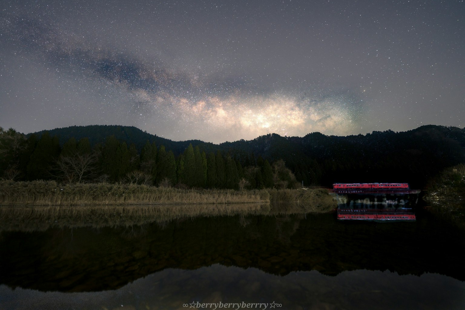 Danau tenang yang memantulkan langit berbintang yang indah dan pegunungan