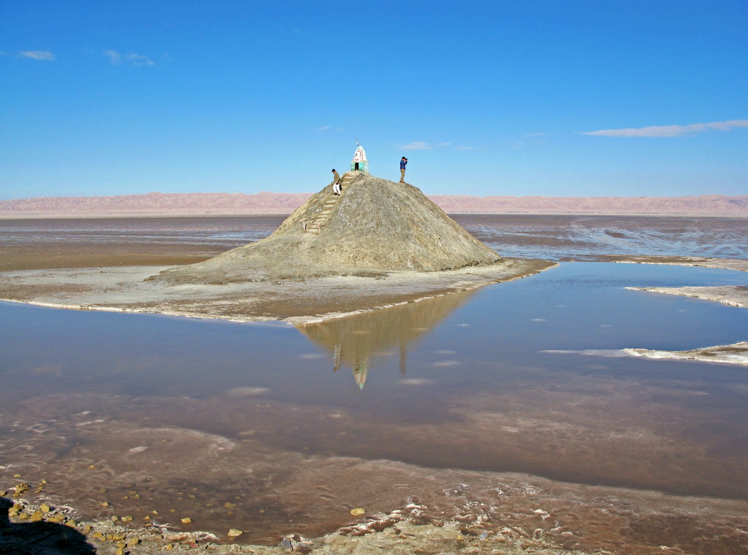 Landscape with people on a salt hill and water reflections